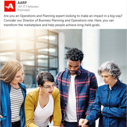 Group of four diverse professionals gathered around a laptop in a modern office, engaging in a discussion.