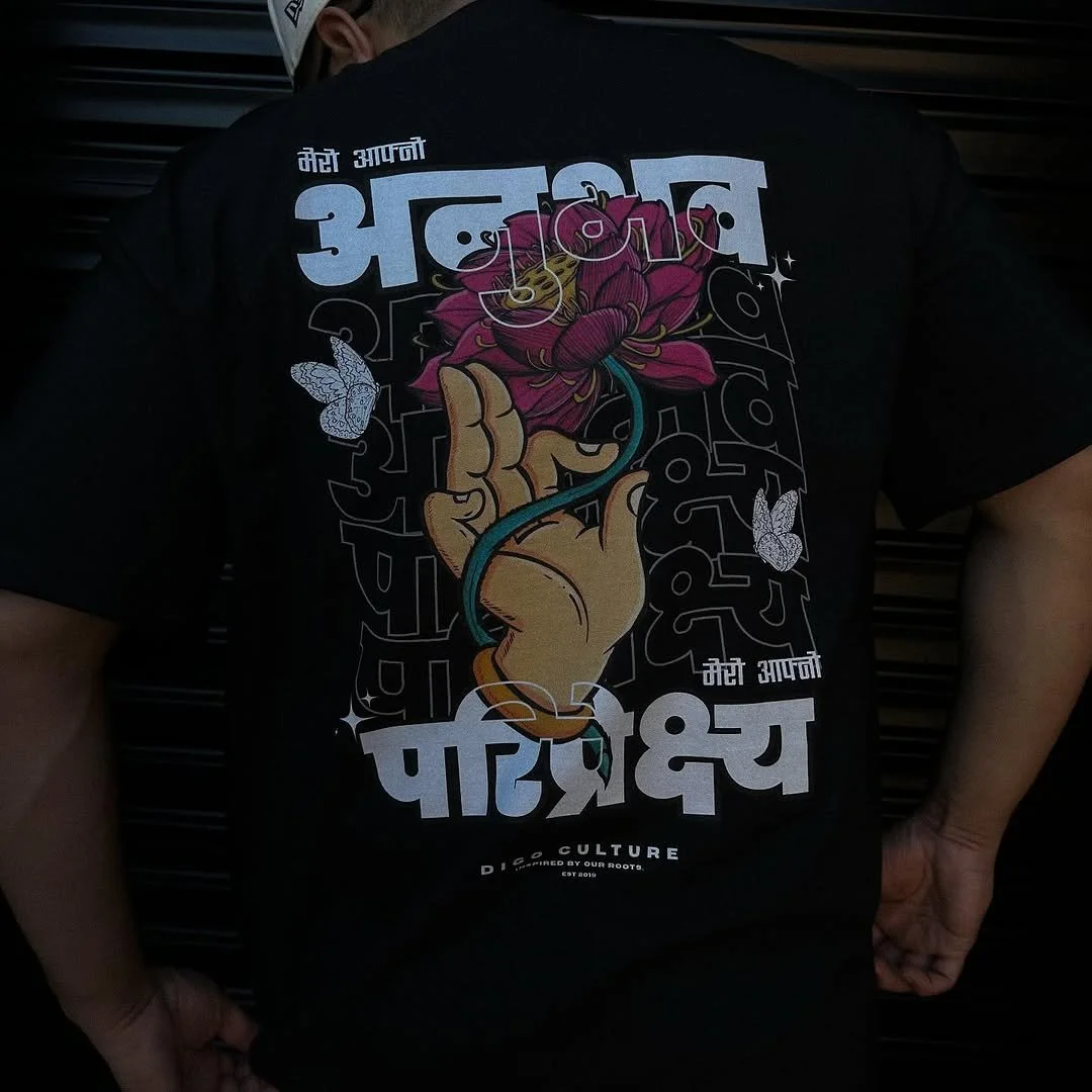 Person wearing a black t-shirt featuring a colorful graphic of a hand holding a pink flower, with white Hindi text and butterflies, and the words 'DISO CULTURE' at the bottom.