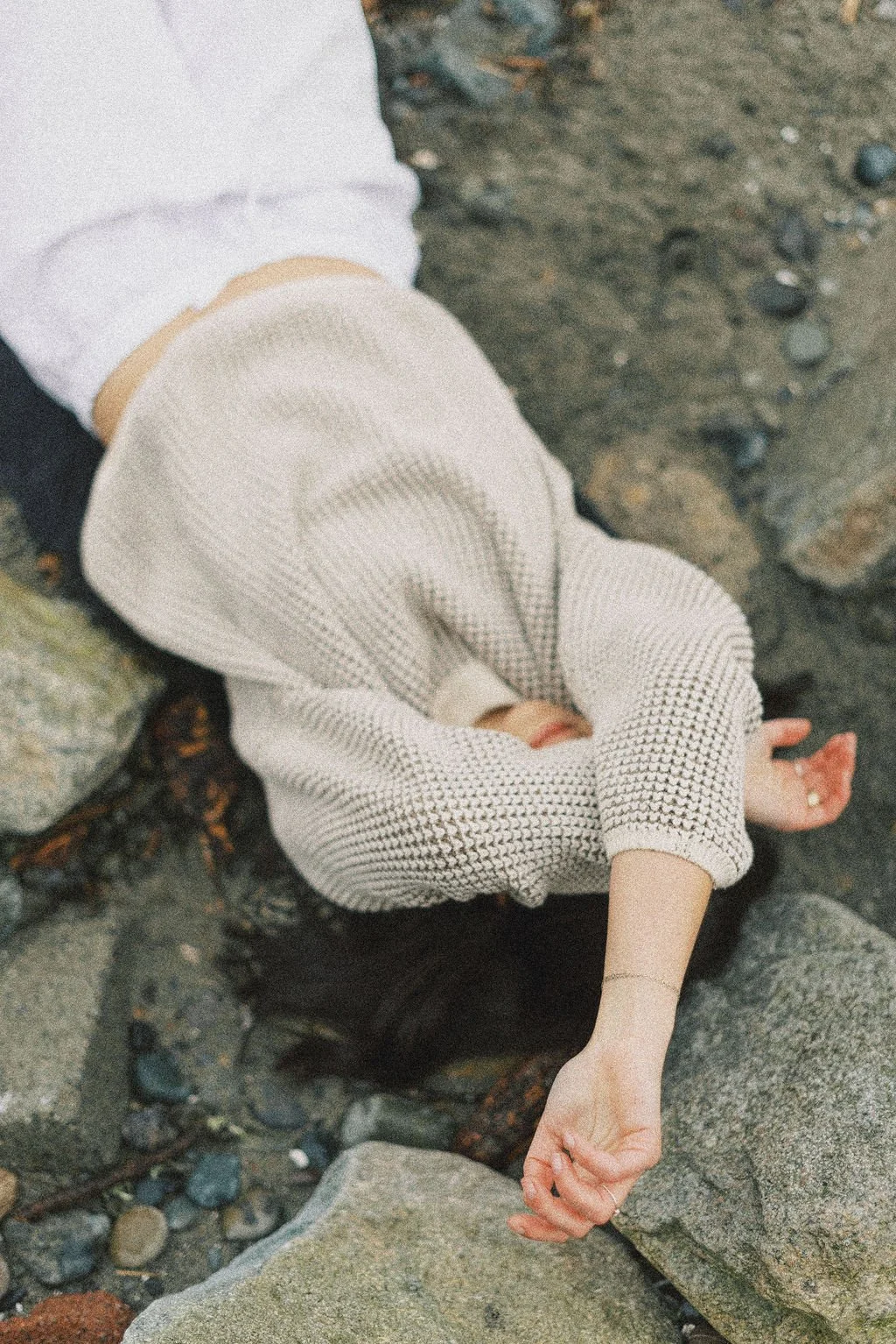 Niki Kairis The Vancouver Death Doula shown laying on the rocks at a beach