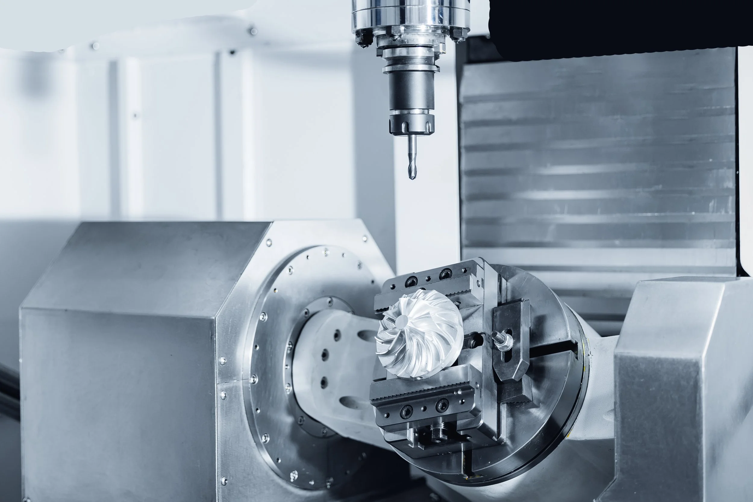 A metallic industrial machine with a rotating part holding a turbine wheel, used for testing or manufacturing high-precision parts.