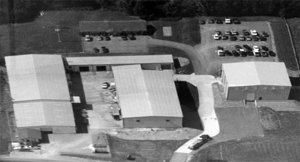 Aerial view of a school campus with multiple buildings, parking lots, and a curved driveway.