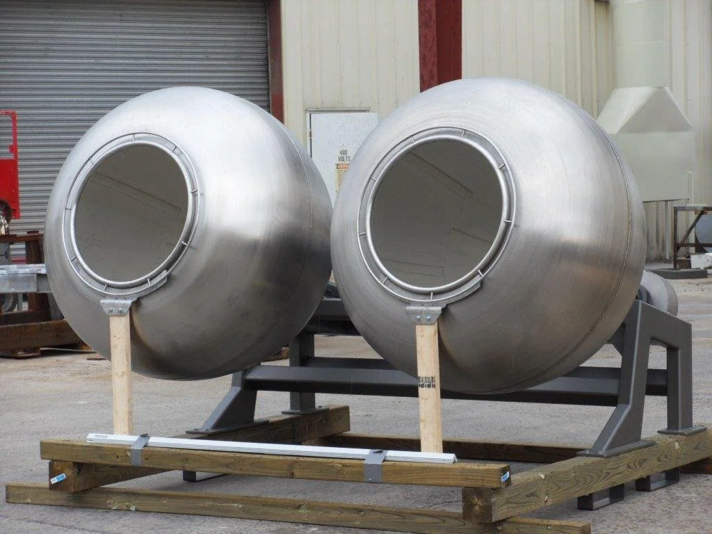 Two large cylindrical metal vessels with open ends, mounted on a wooden and metal frame.
