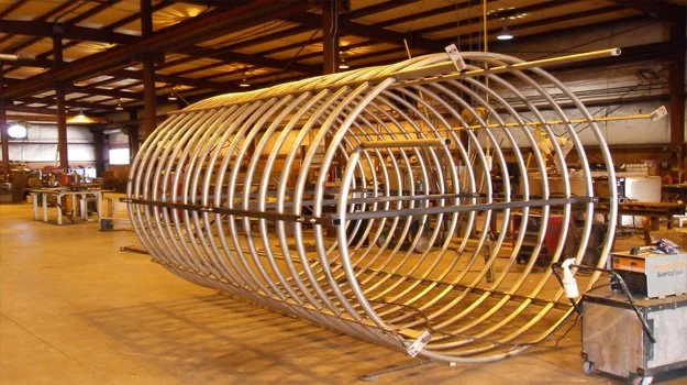 Large metallic ribbed cylindrical structure inside a workshop or factory.
