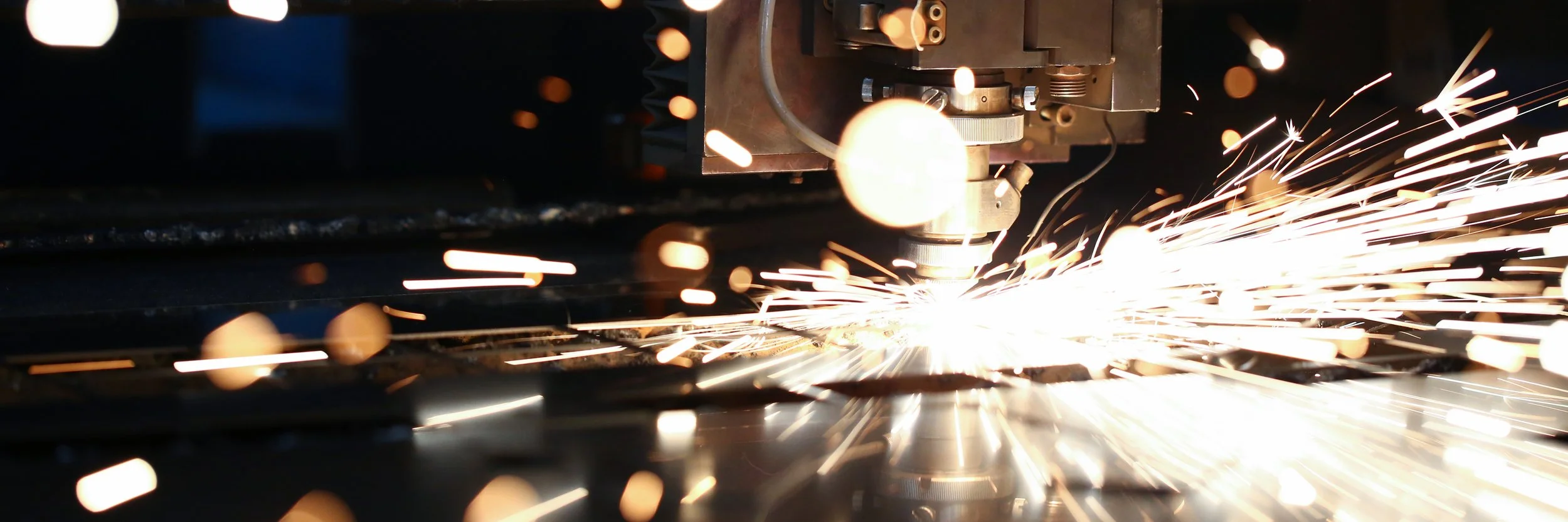 A robotic welding machine sparks as it welds metal in an industrial setting.