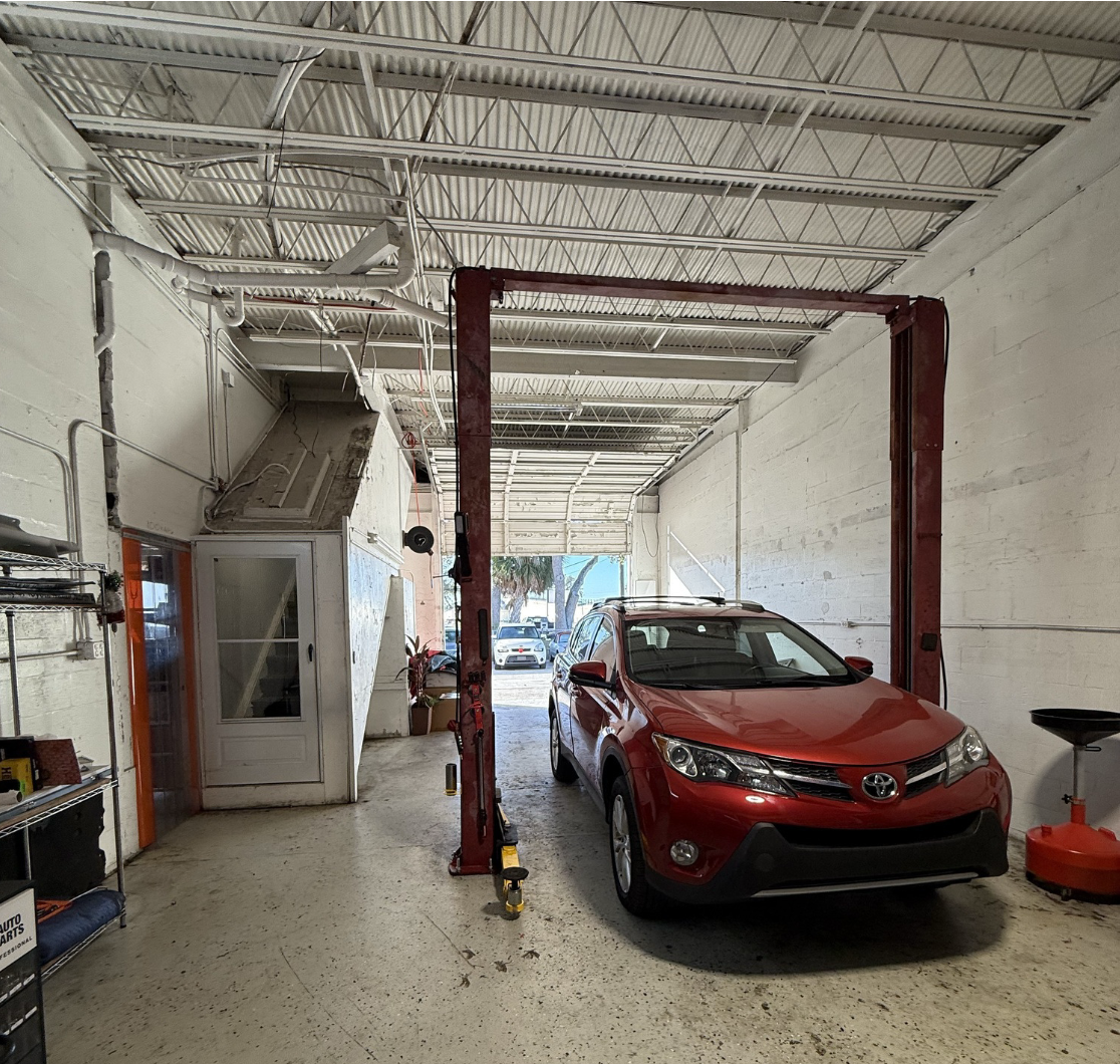Service bay inside industrial warehouse at 5671 McIntosh Road in Sarasota, Florida, featuring vehicle lift and open bay access