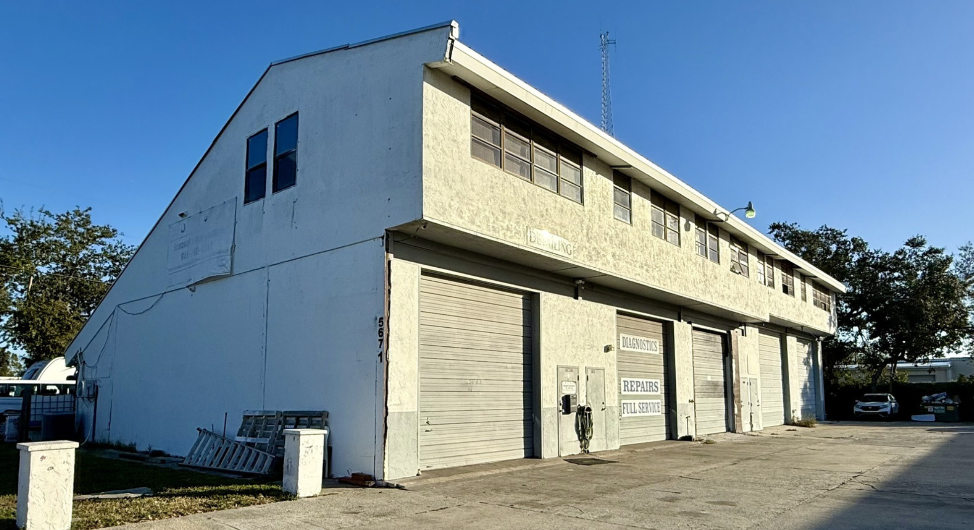 Exterior view of industrial warehouse for sale at 5671 McIntosh Road in Sarasota, Florida with multiple roll-up bay doors