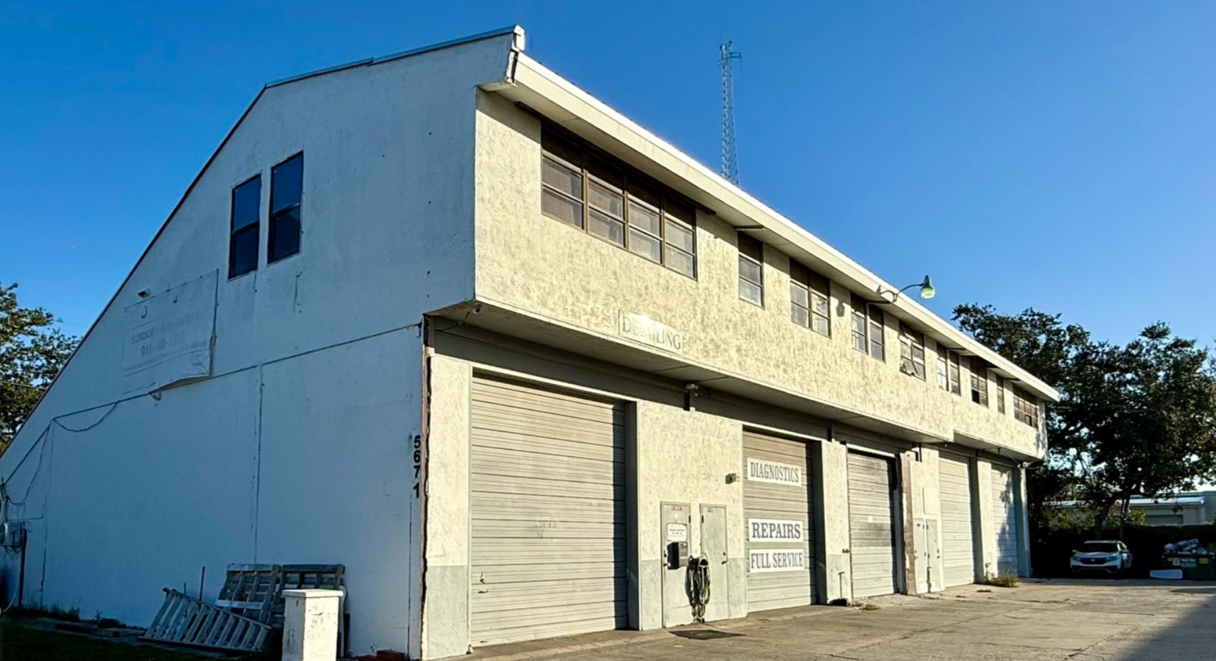 Exterior view of industrial warehouse for sale at 5671 McIntosh Road in Sarasota, Florida with multiple roll-up bay doors