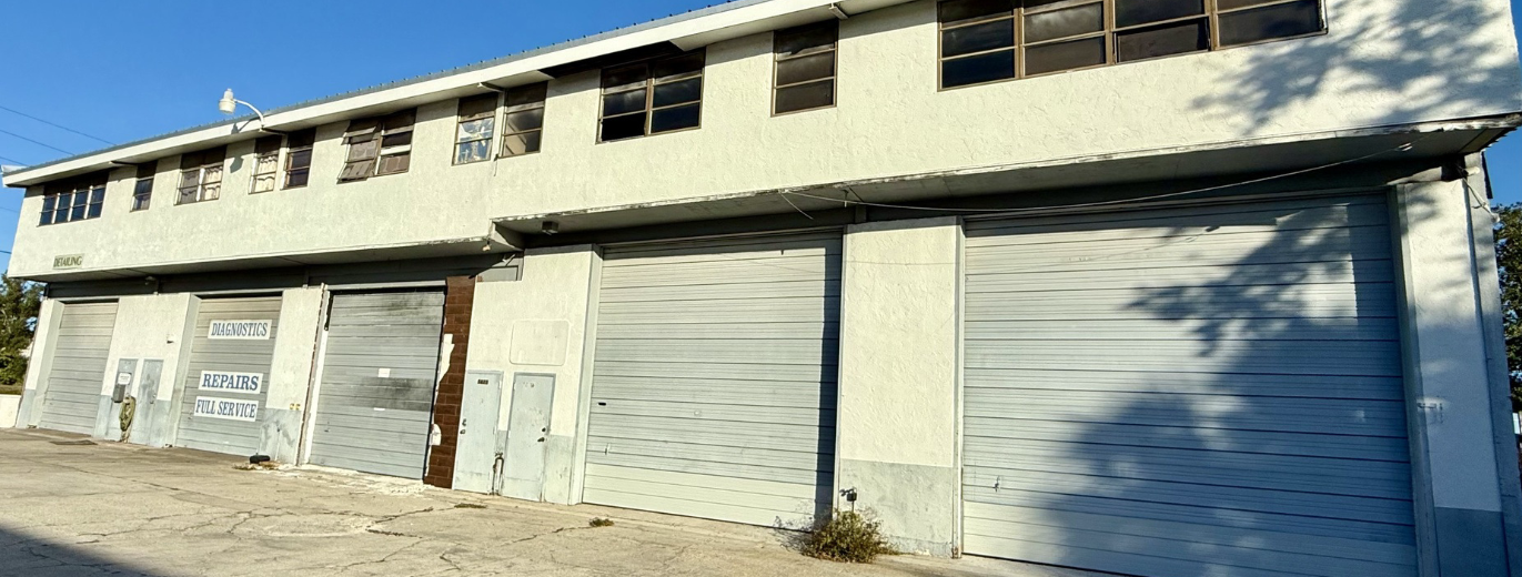 Side angle view of industrial warehouse for sale at 5671 McIntosh Road in Sarasota, Florida with multiple roll-up bay doors