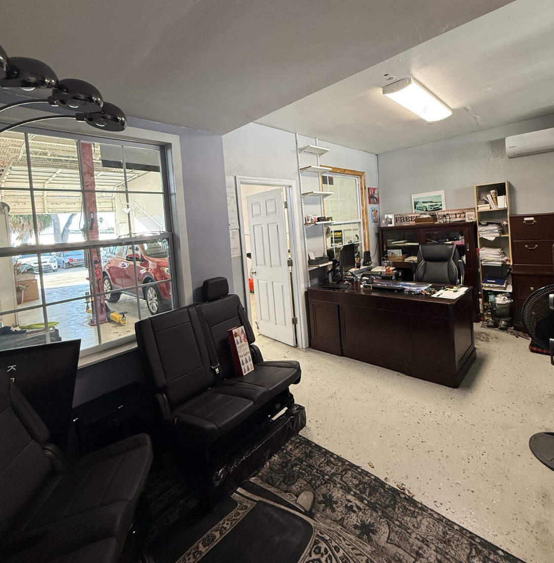 Interior office space inside industrial warehouse at 5671 McIntosh Road in Sarasota, Florida, with desk, seating, and view into service bay