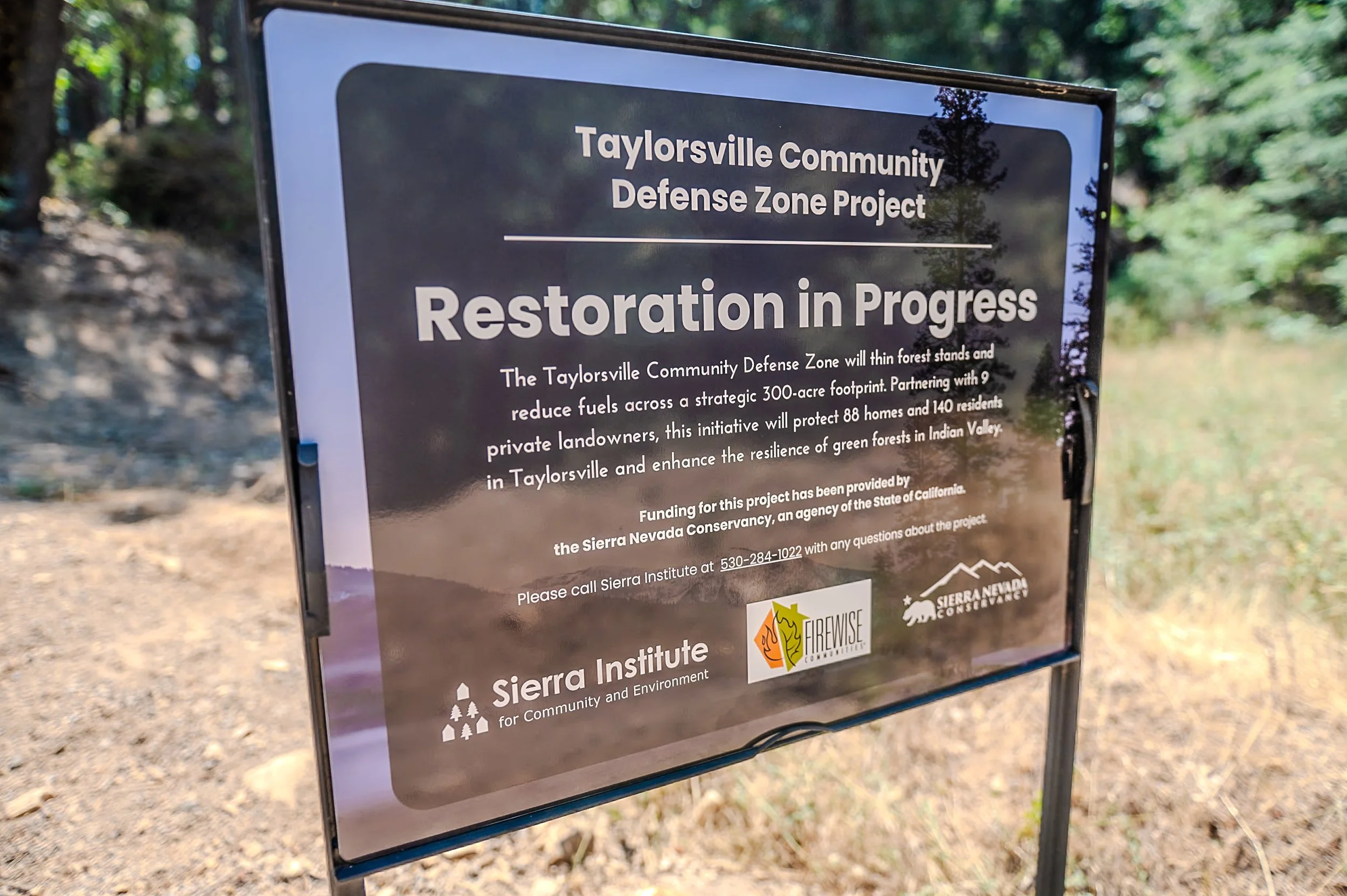 Sign about the restoration project in Taylorsville, showing the Taylorsville Community Defense Zone Project, emphasizing thinning forest stands to reduce fuels, and partnerships with Sierra Nevada Conservancy and Sierra Institute.