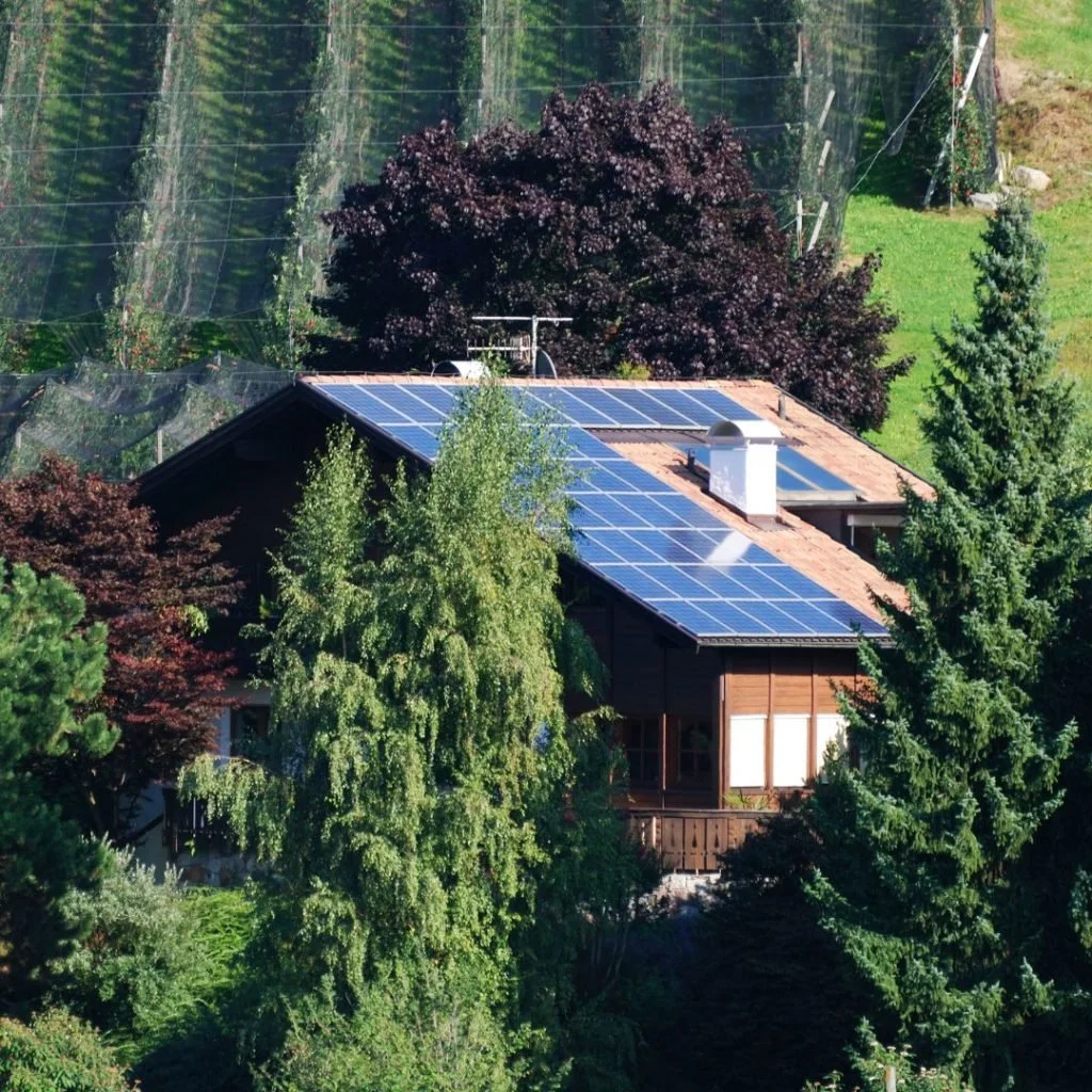 Maison entourée d'arbres avec des panneaux solaires sur le toit.