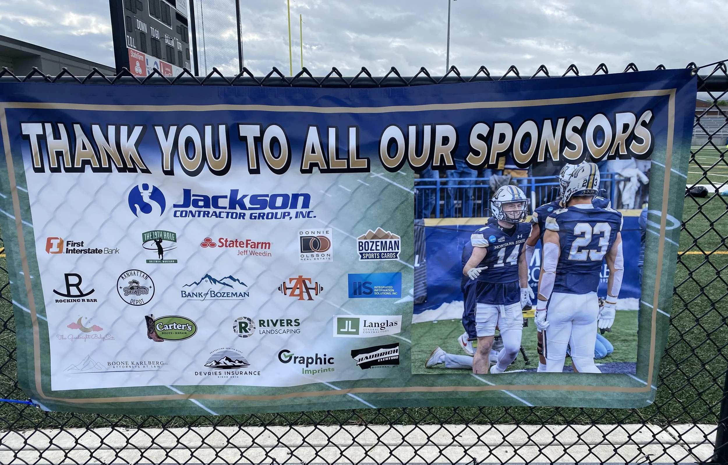 A thank you banner for sponsors of a football event, featuring logos of various sponsors, and a picture of two football players in uniform on a football field.