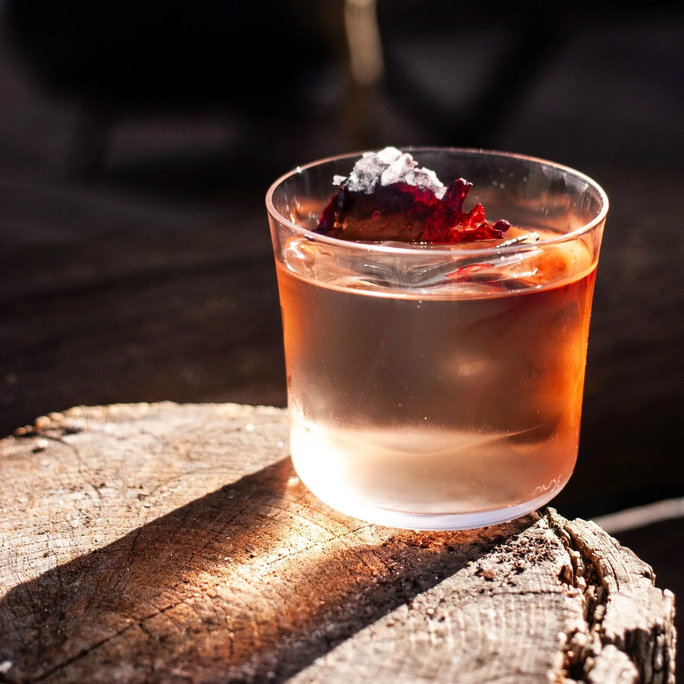 Vaso de cóctel con hielo y rodaja de fruta en un ambiente oscuro y cálido. Contenido de redes sociales.