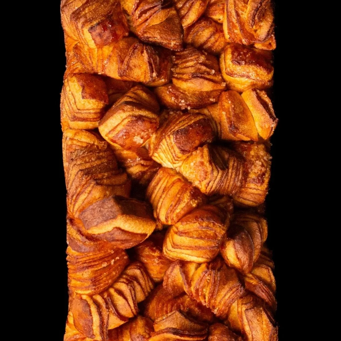 Manja de croissants rellenos de chocolate apilados en una fila sobre fondo negro. Contenido de redes sociales.