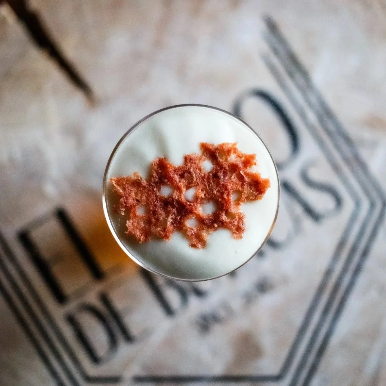 Vaso con bebida blanca y decorada con una galleta de arce en la parte superior, visto desde arriba. Contenido de redes sociales.