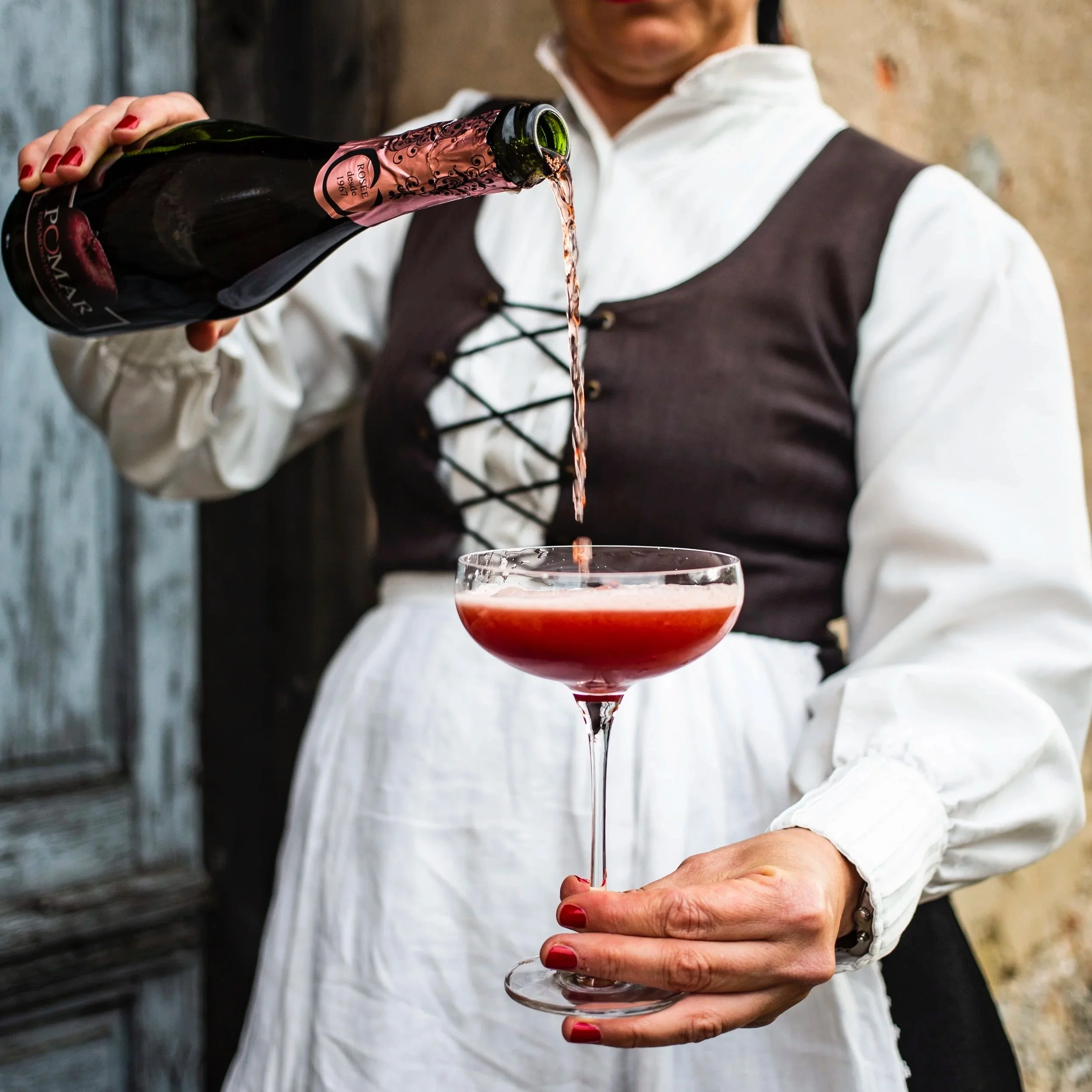 Una mujer sirviendo sidra espumosa rosada en una copa de cóctel. Contenido de redes sociales.