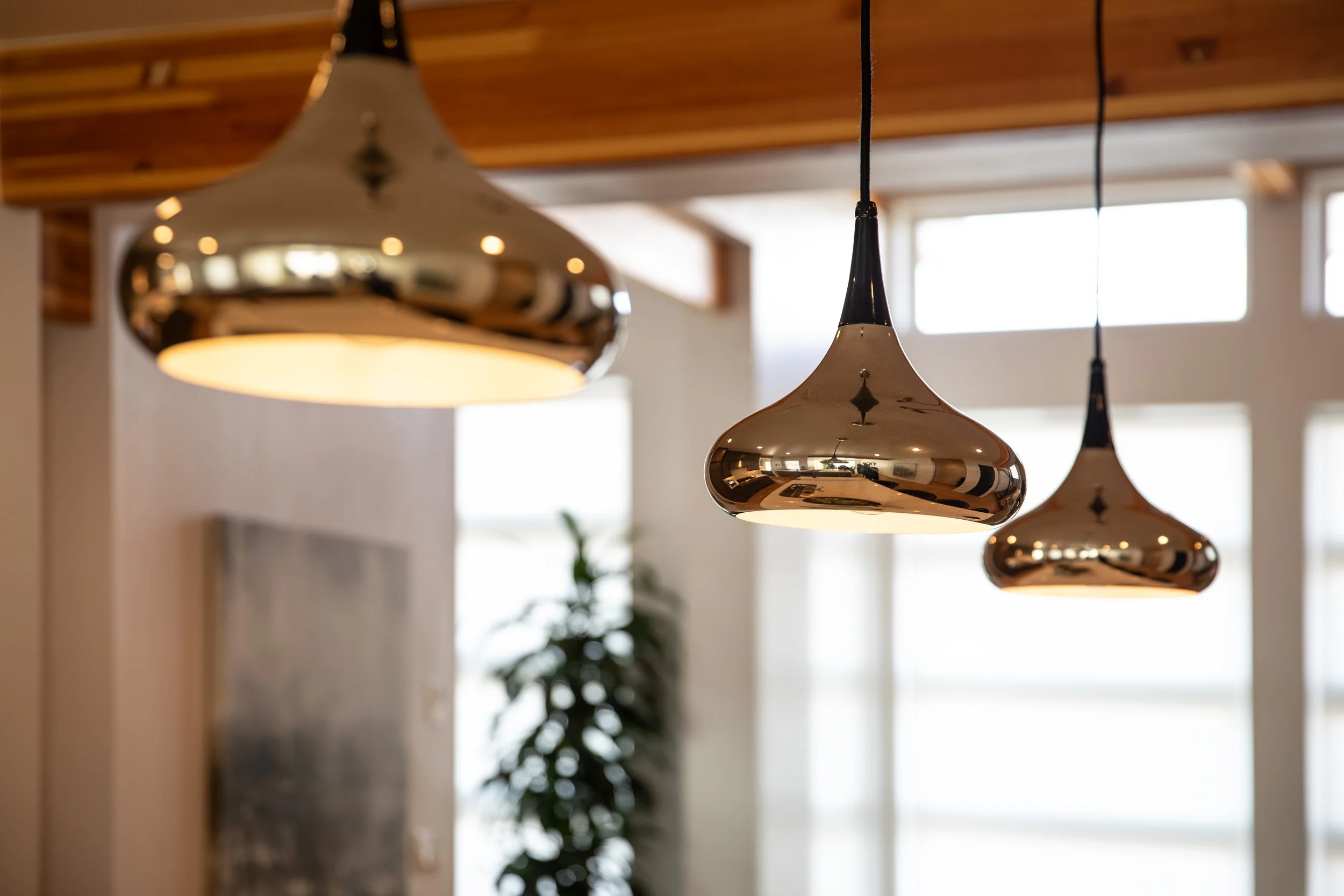 Three hanging pendant lights with reflective metallic finishes in an interior space.