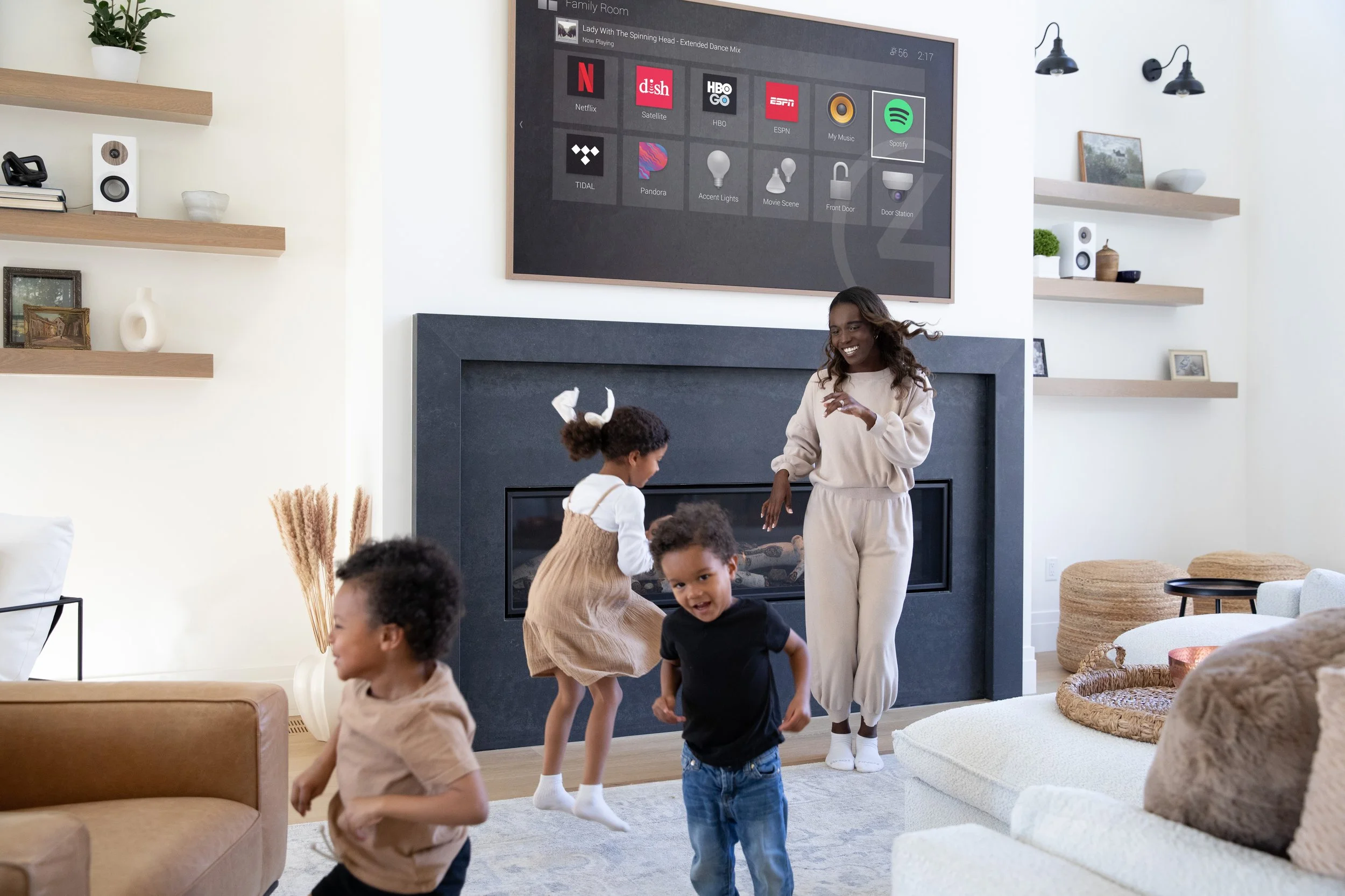A woman and four children are in a living room joyfully dancing and playing.