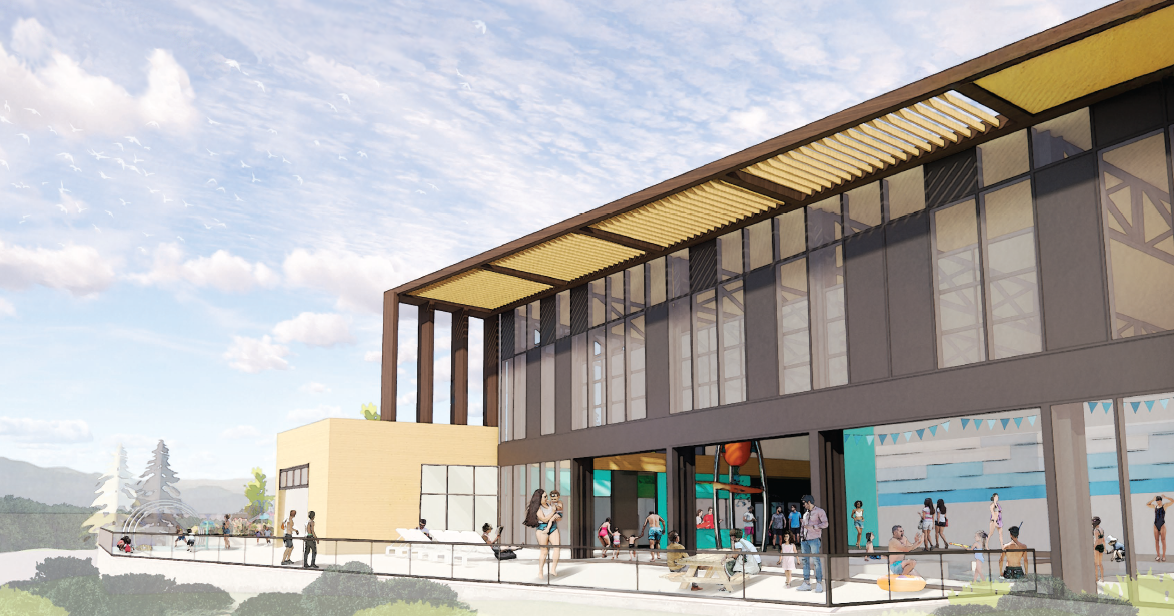 Modern aquatic center with large glass windows, outdoor area with people swimming, playing, and relaxing by the pool, and a scenic background of trees and mountains under a partly cloudy sky.