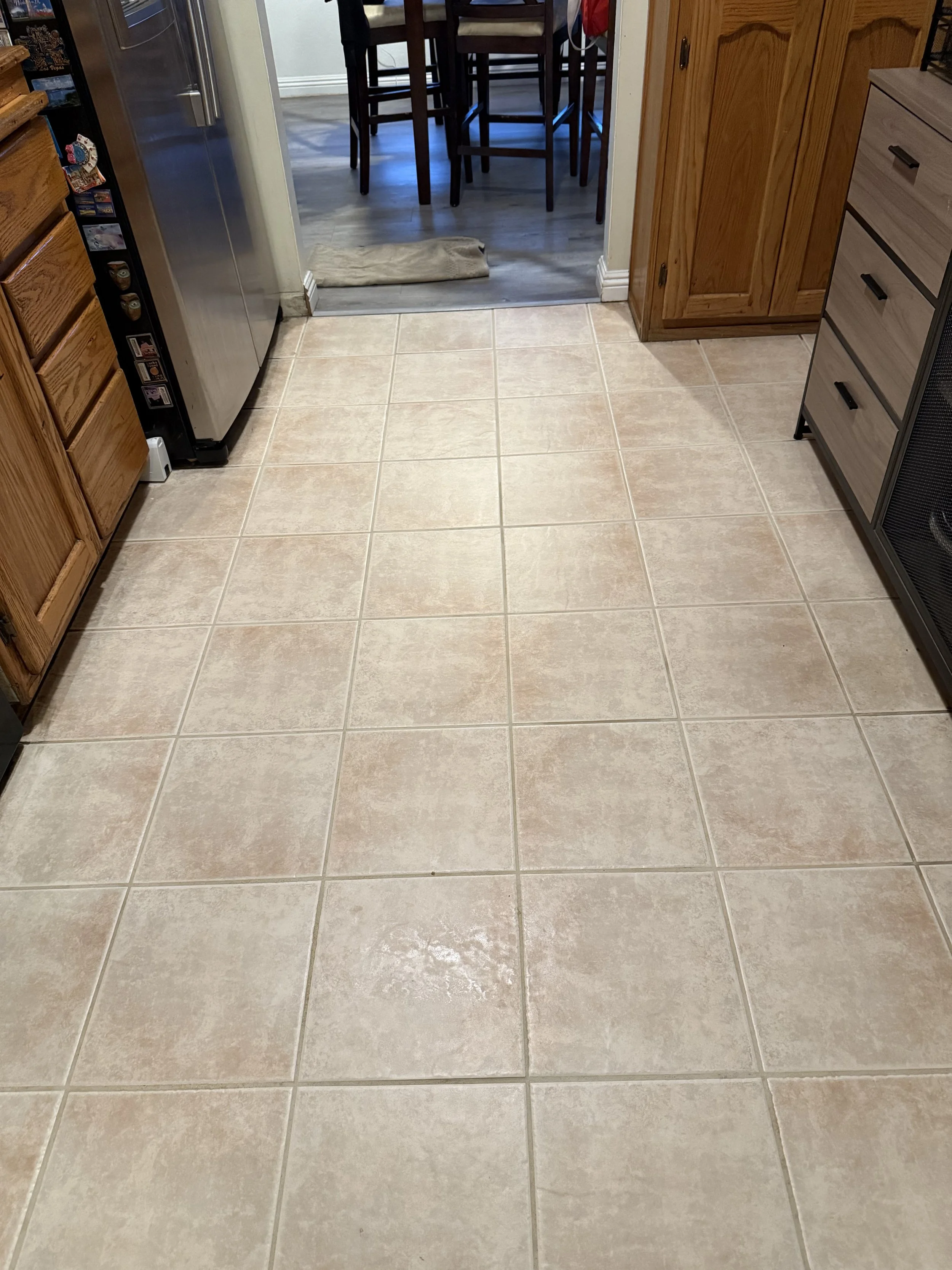 A view from a kitchen floor looking into an adjacent dining area with wooden chairs and a table.