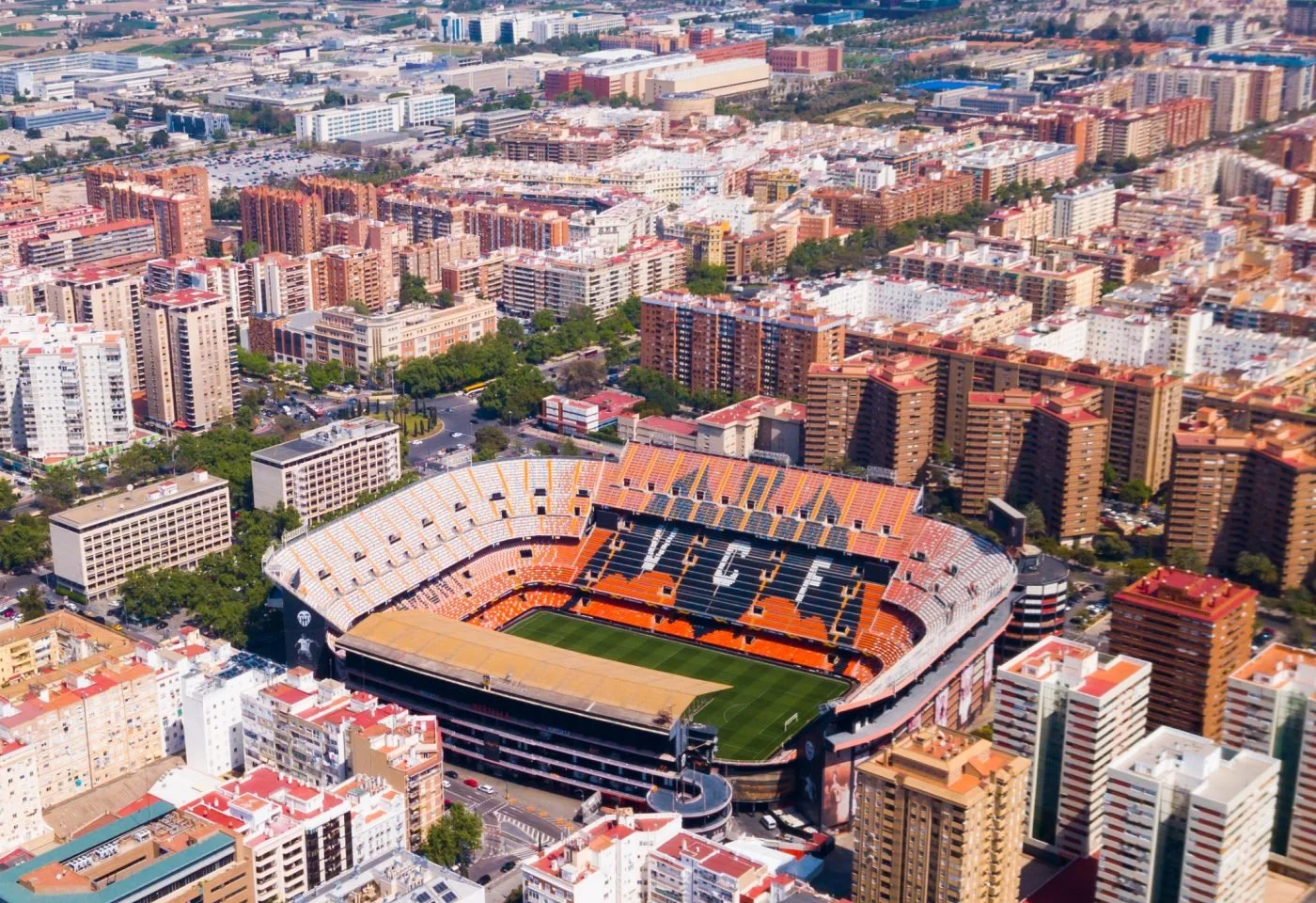 An aerial view of a large sports stadium surrounded by high-rise buildings in a city.