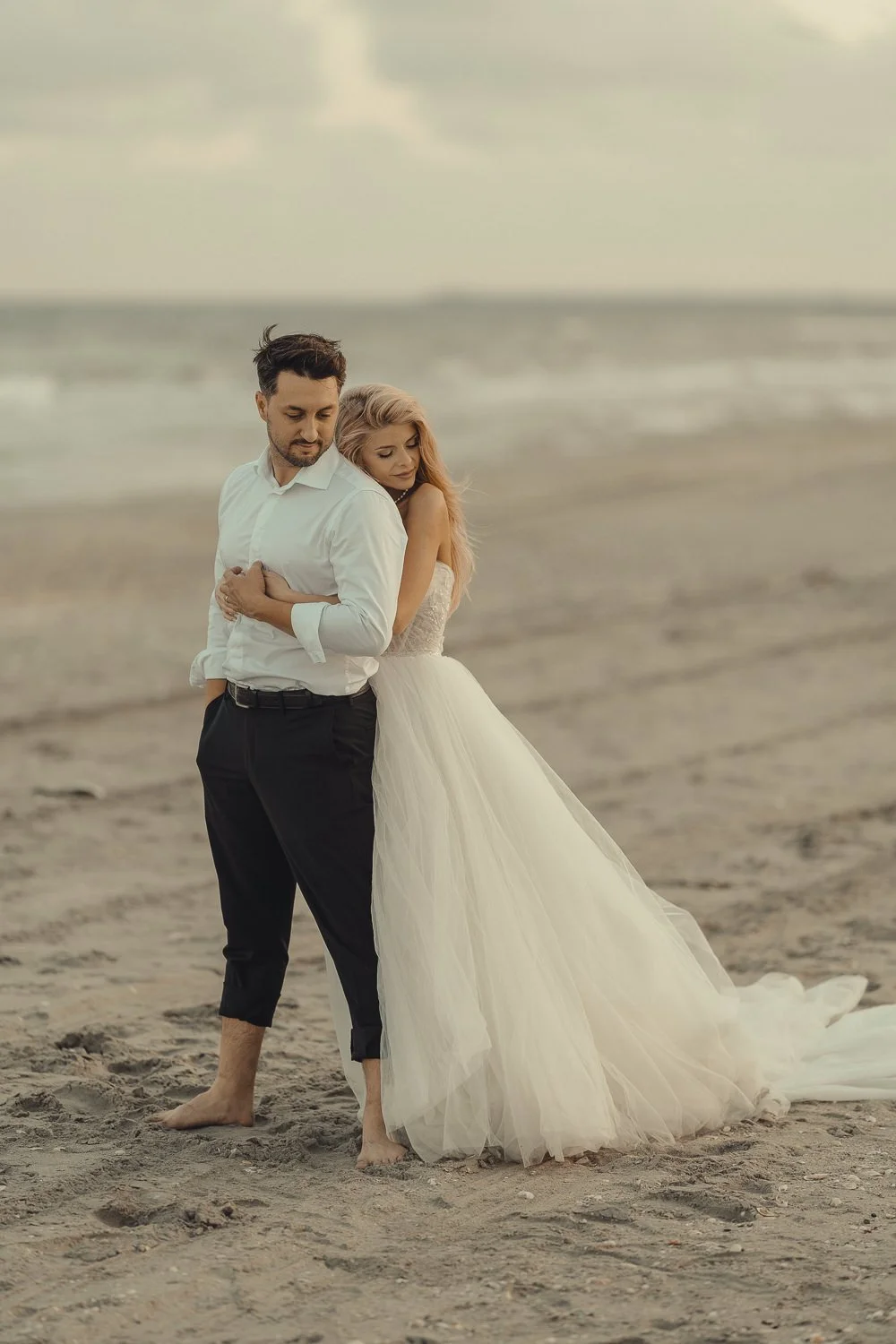 Fotografie de nuntă artistică cu un cuplu îmbrățișat în lumină naturală, realizată într-un stil cinematic, cu emoție autentică și estetică elegantă.