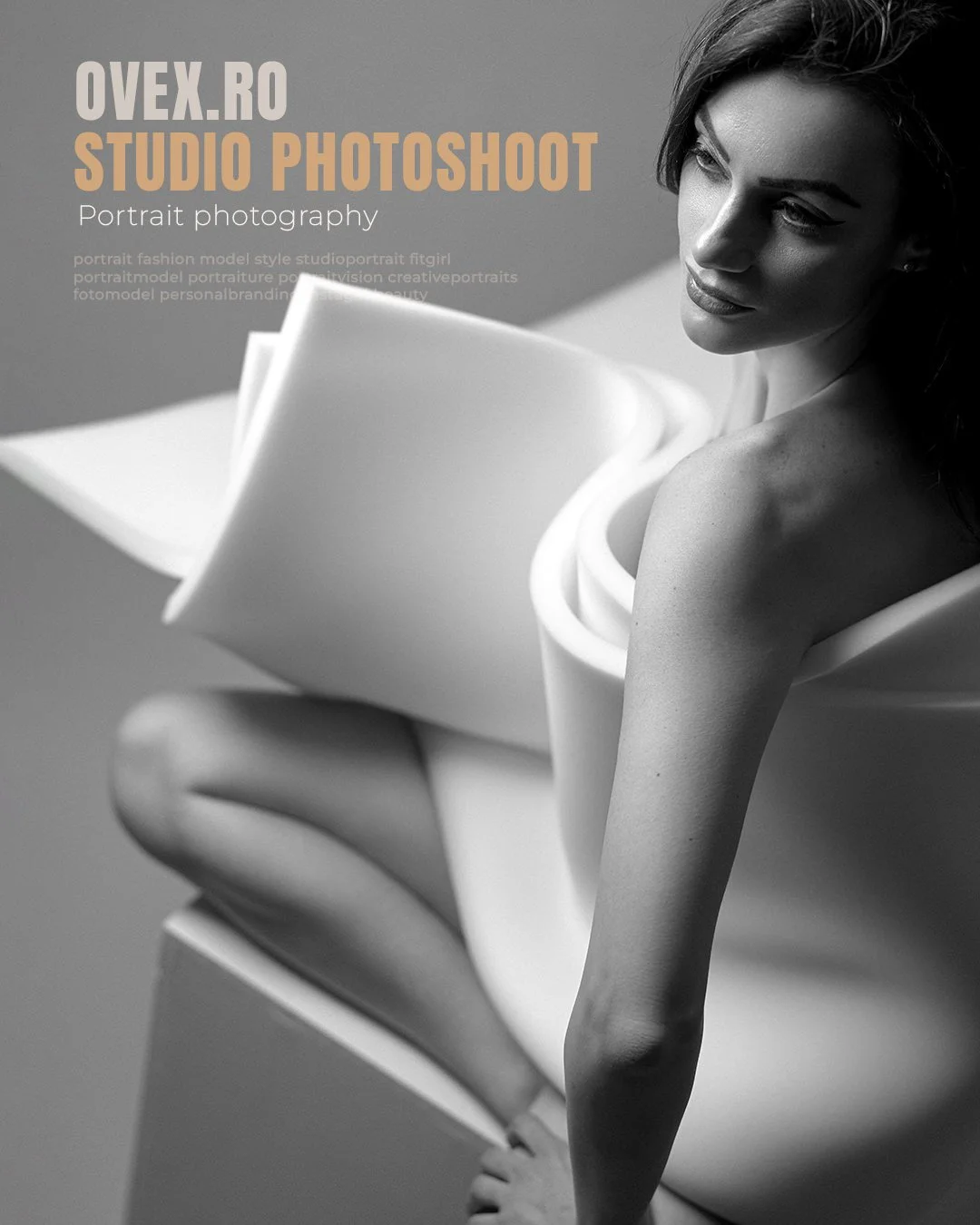 Black and white photo of a woman with long hair, posing with her body turned to the side and looking downward, wrapped in a white fabric or paper sculpture, with text overlay about a Photoshop portrait photography studio.
