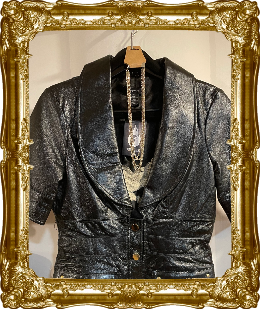 Born Again Consignment Parlor. Printers Row. Black leather jacket displayed inside a decorative gold frame.
