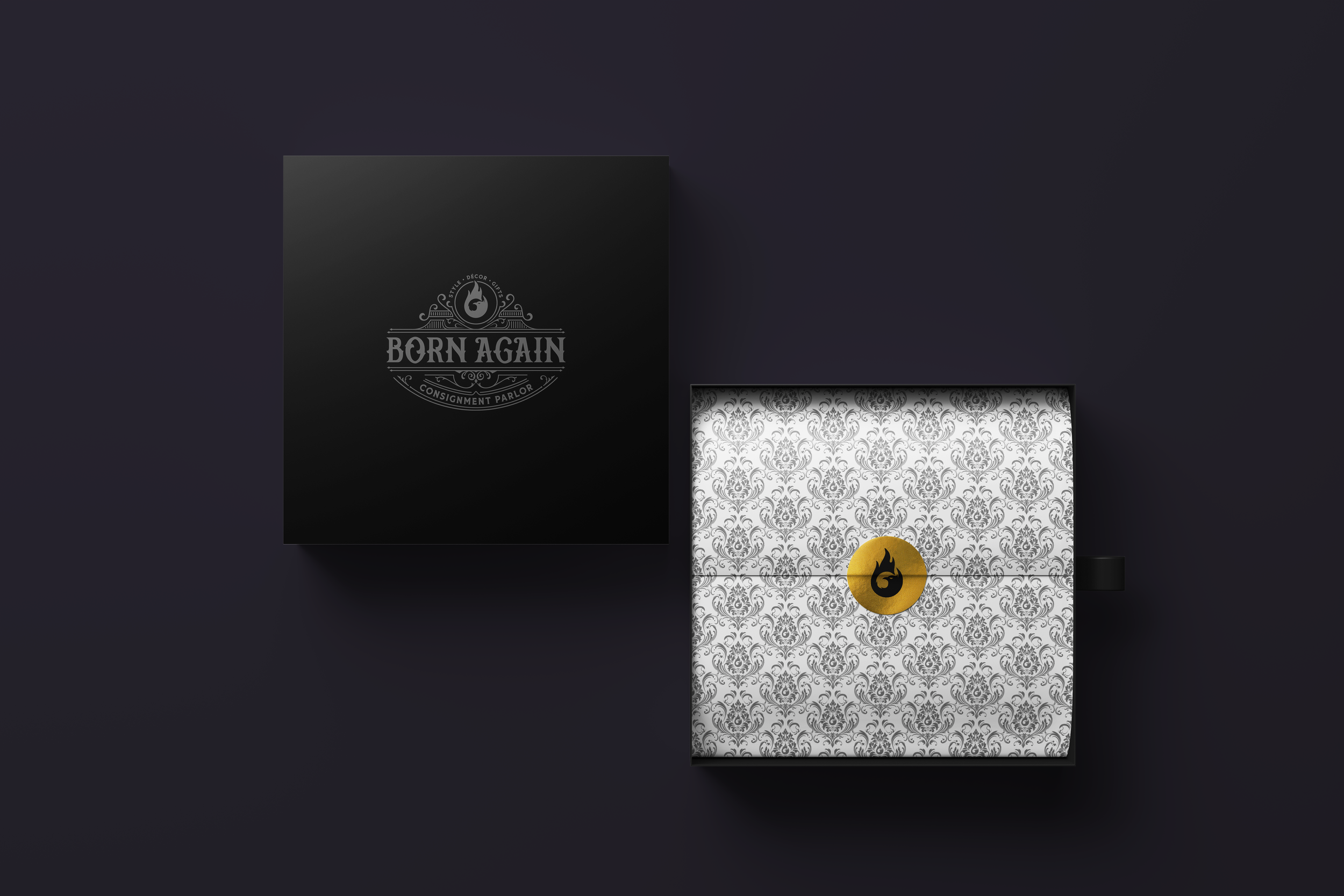 Black box with a logo reading "Born Again Consignment Parlor," and a decorative, patterned white interior with a gold sticker featuring a logo.