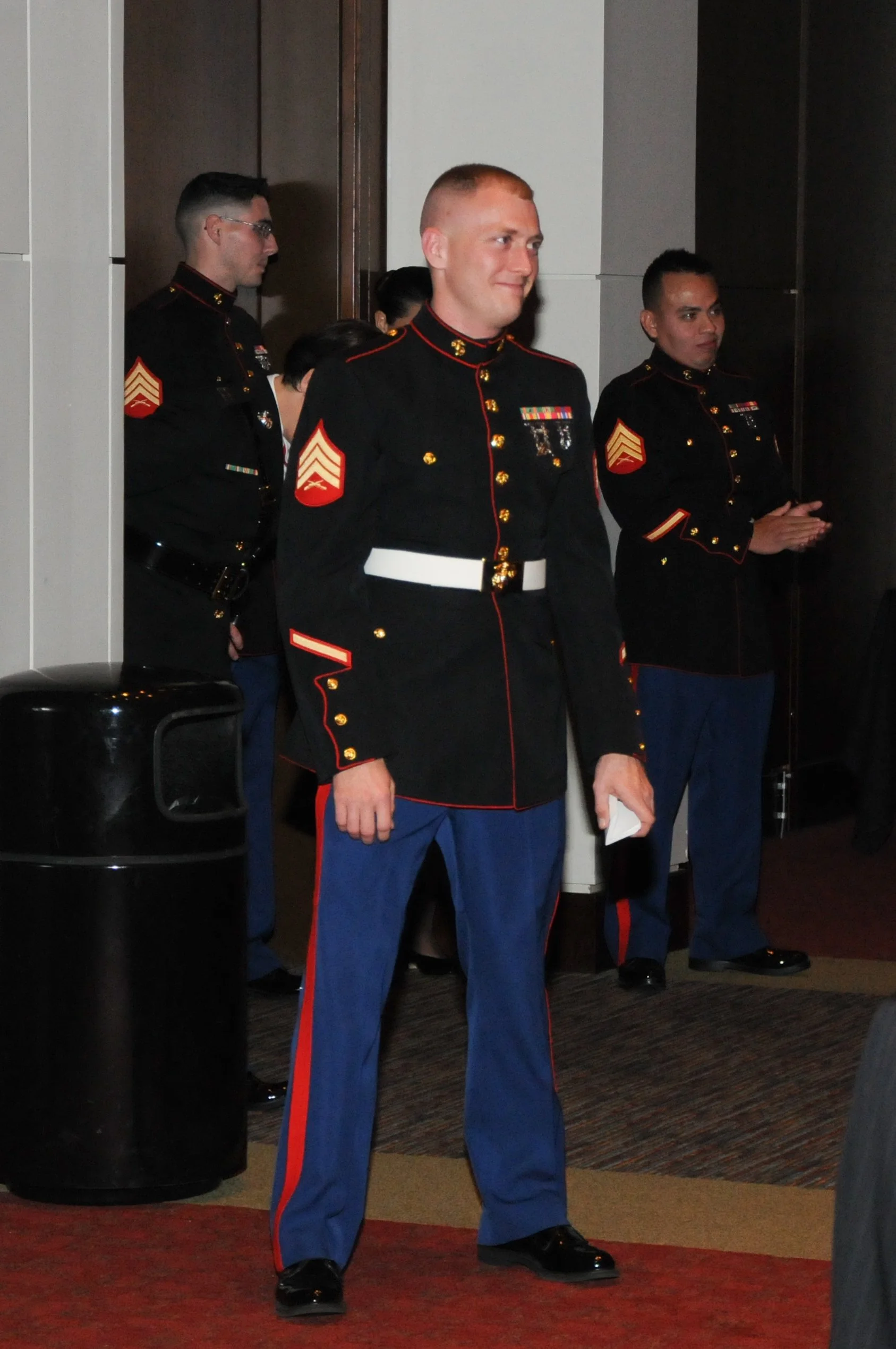 A group of U.S. Marines in dress uniform, standing indoors at an event.