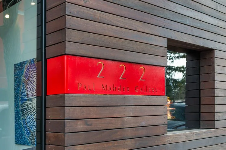 Exterior of Paul Mahder Gallery with horizontal wood paneling and red gallery sign showing the address 222 and name.