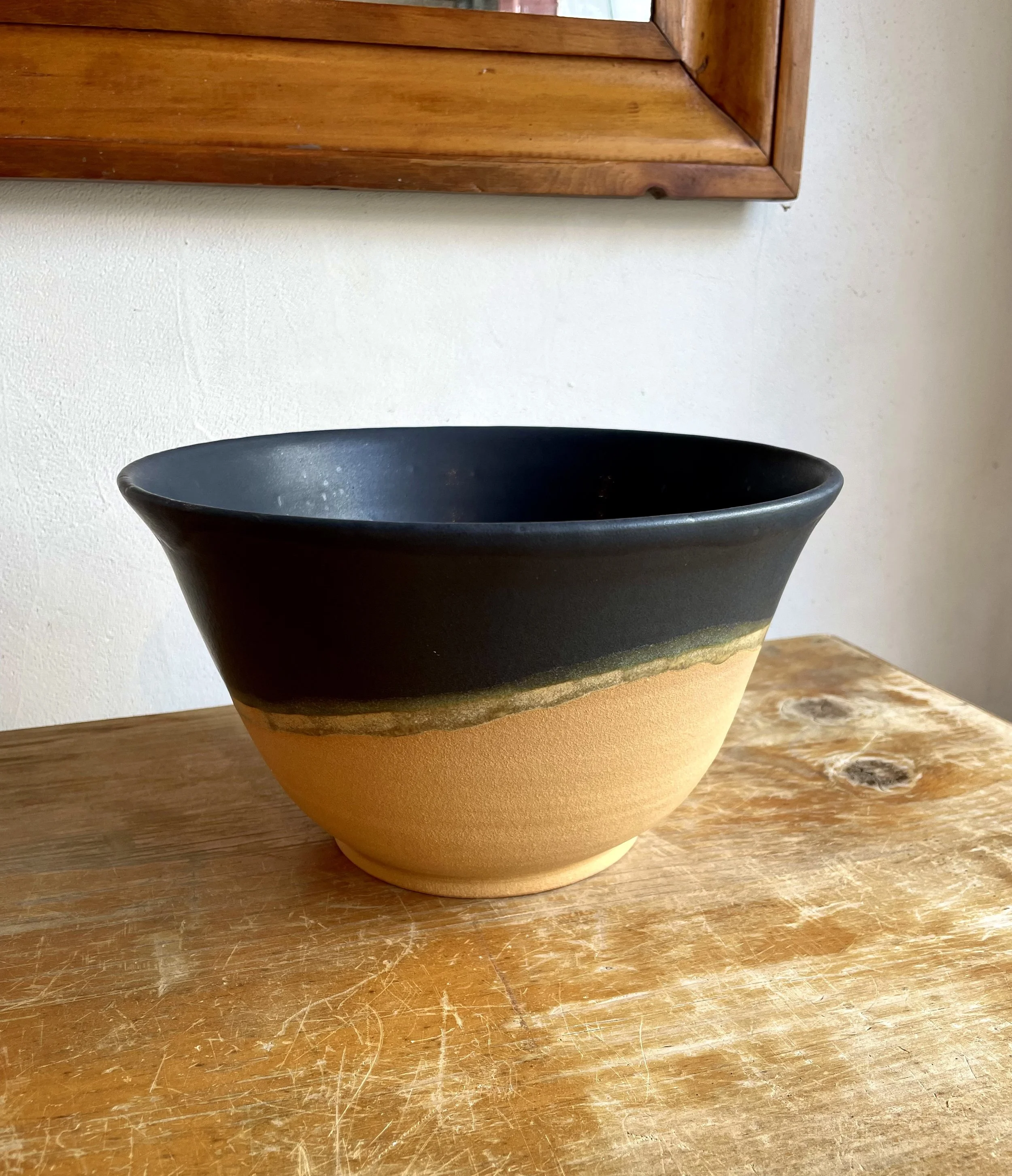 Large hand-thrown salad bowl in a warm desert gold clay body with a black satin glaze, and a ring of golden honey