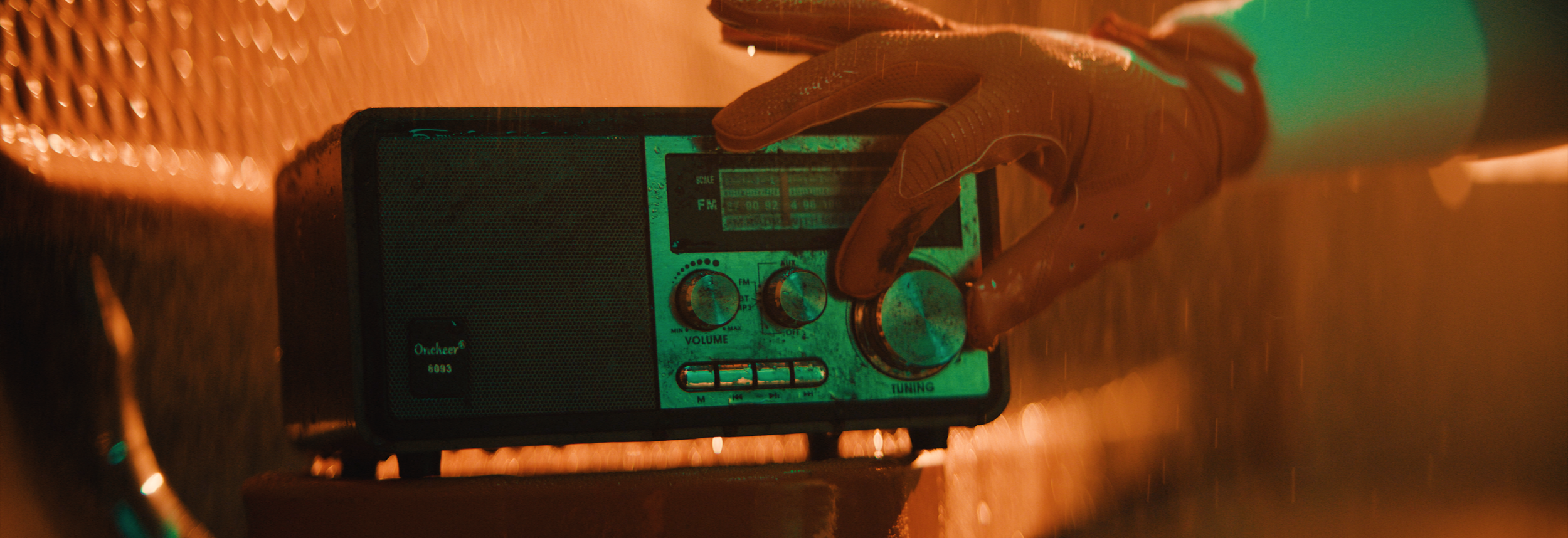 Close-up of a gloved hand adjusting the tuning knob on a vintage portable radio with an orange and green glow.  Cleveland Browns. Sports director of photography camera operator. Arri Alexa 35 anamorphics.