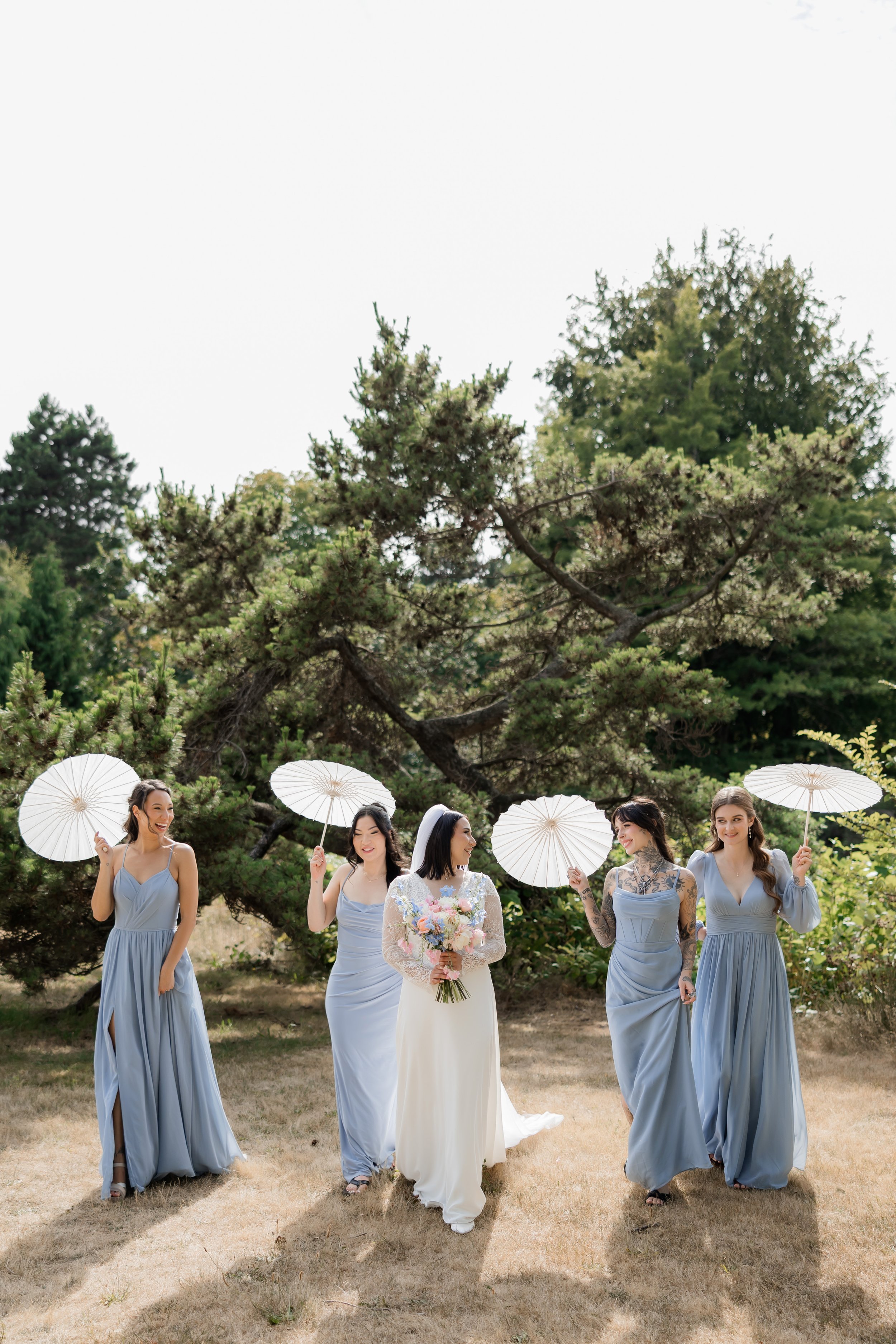 Bridesmaids walking together with white parasols