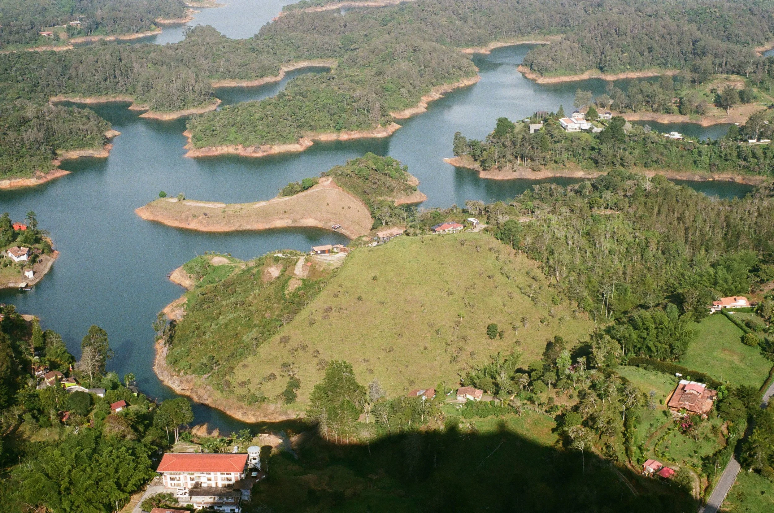 Aerial view of a lake with numerous small islands, surrounded by lush green hills and scattered houses.
