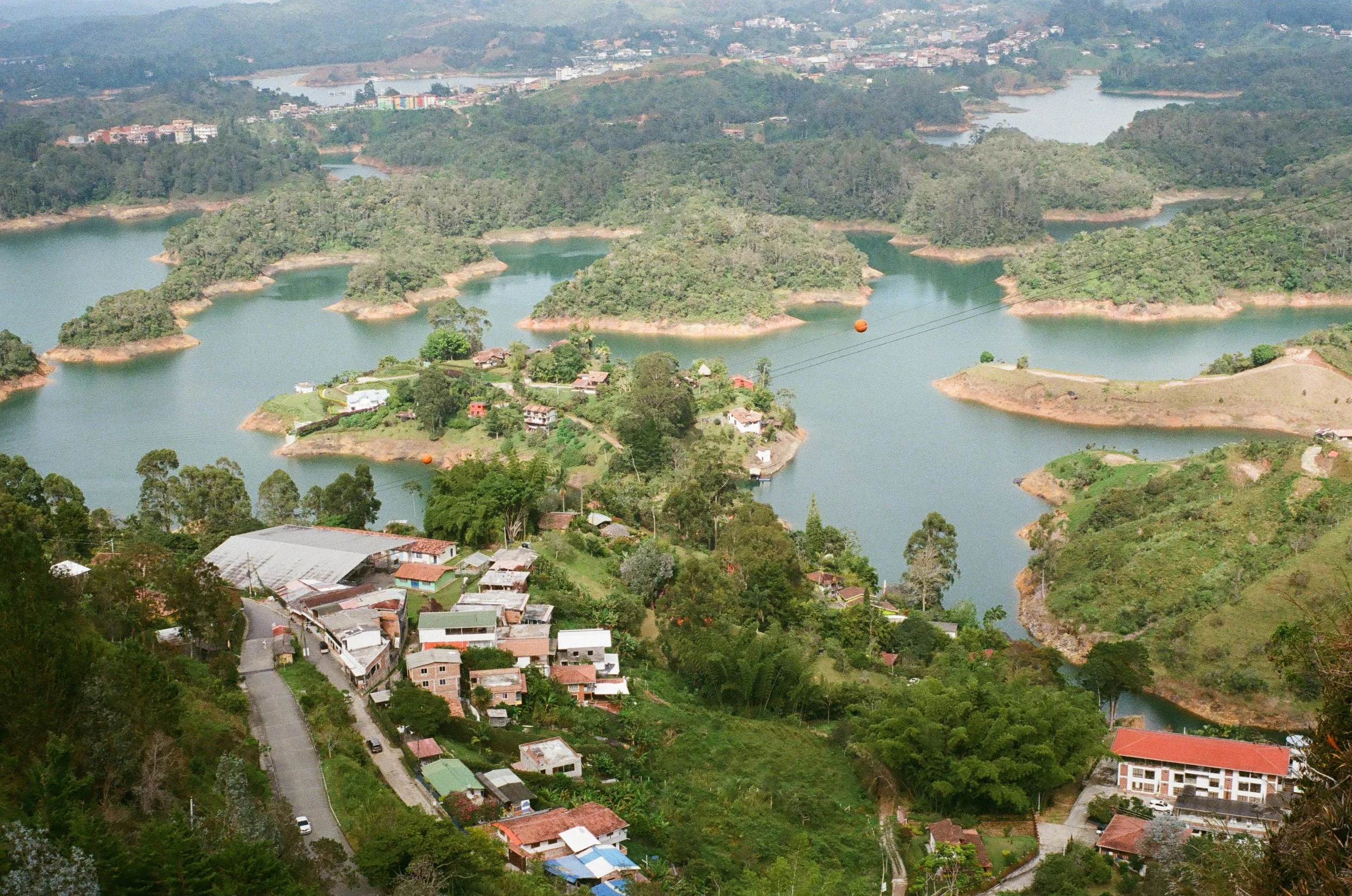 Aerial view of a landscape with lakes, islands, and a small town with houses and greenery.