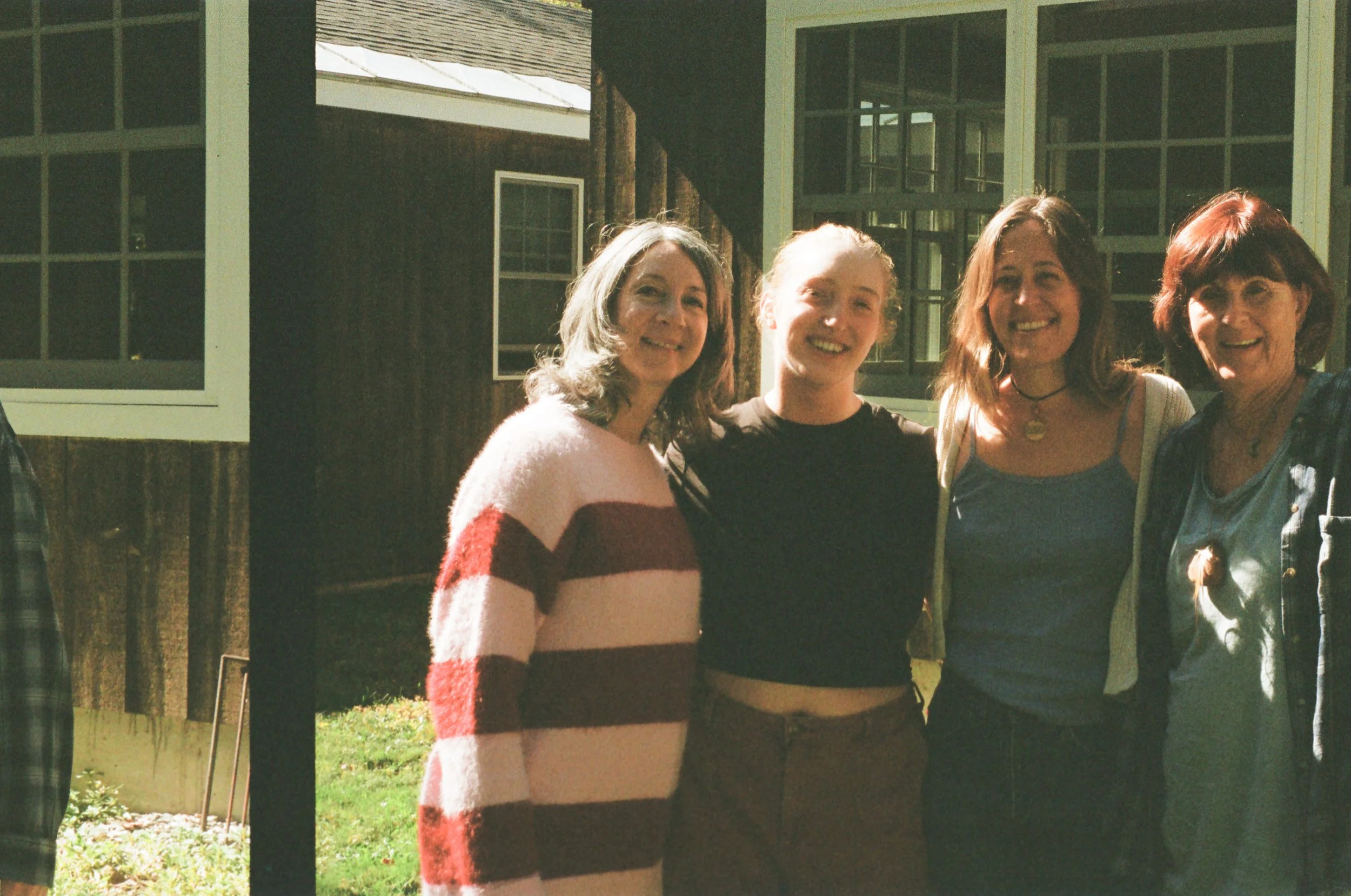 Four women standing outdoors in front of a building, posing and smiling for a photo.