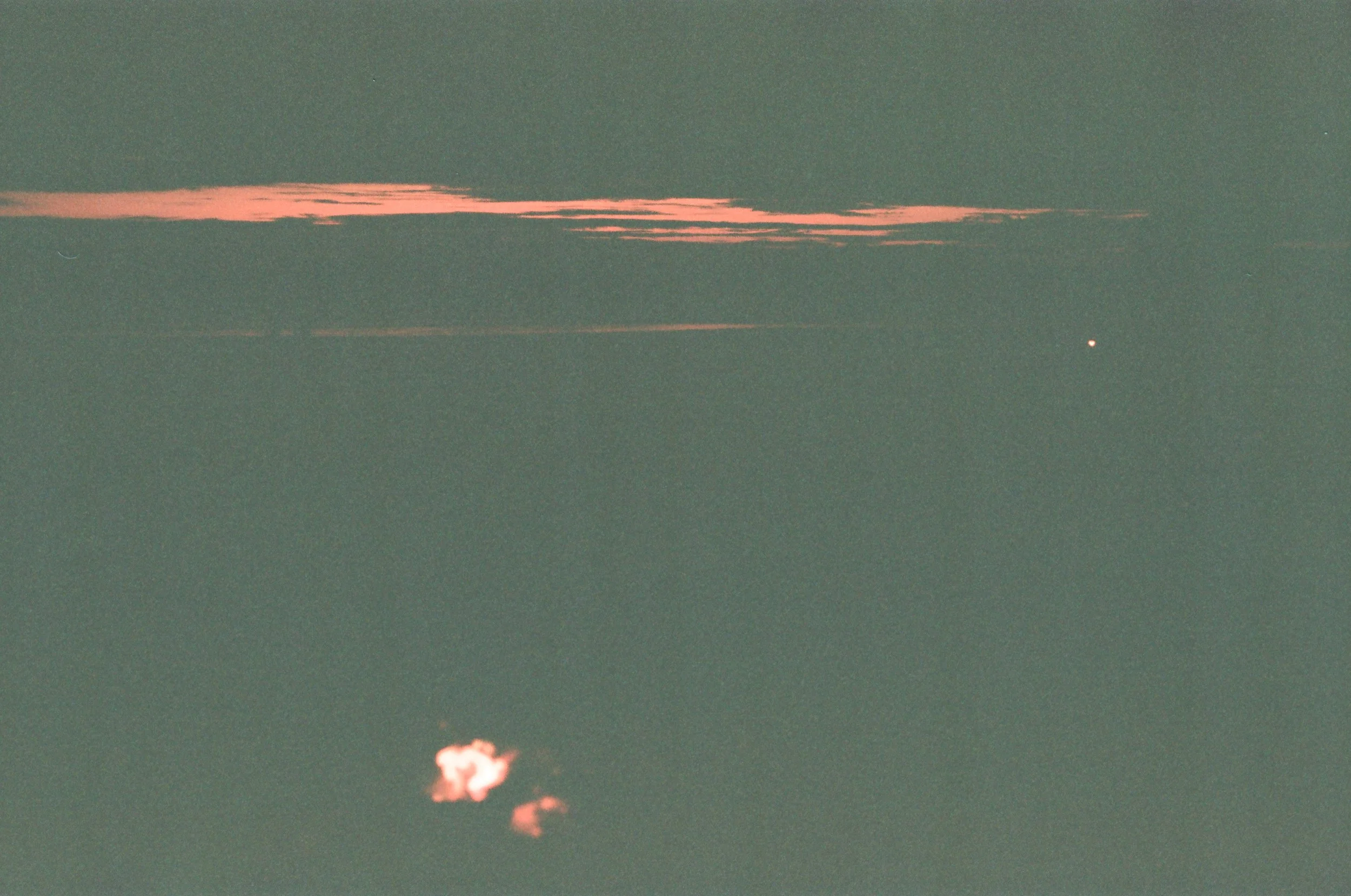 Cloudy sky with pinkish clouds and a small bright object, possibly a star or planet, at night.