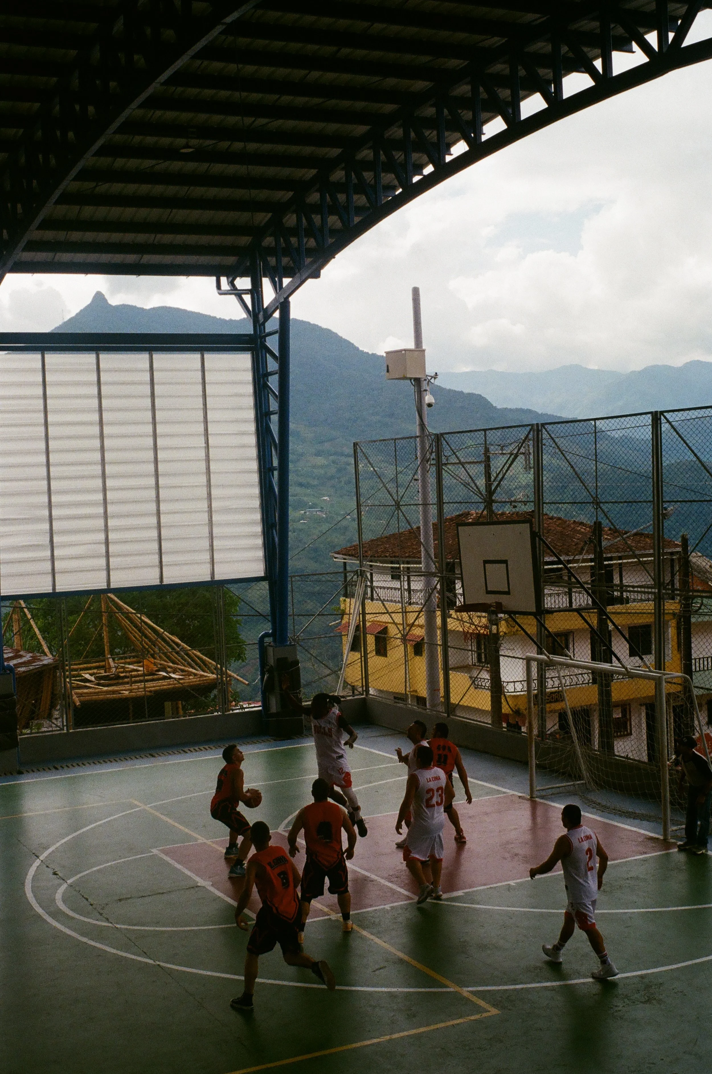 Children playing basketball on an indoor court with a mountain view outside.