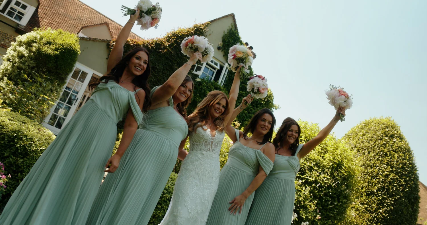 Bride and bridesmaids celebrating in the outdoor grounds at Old Luxters Barn