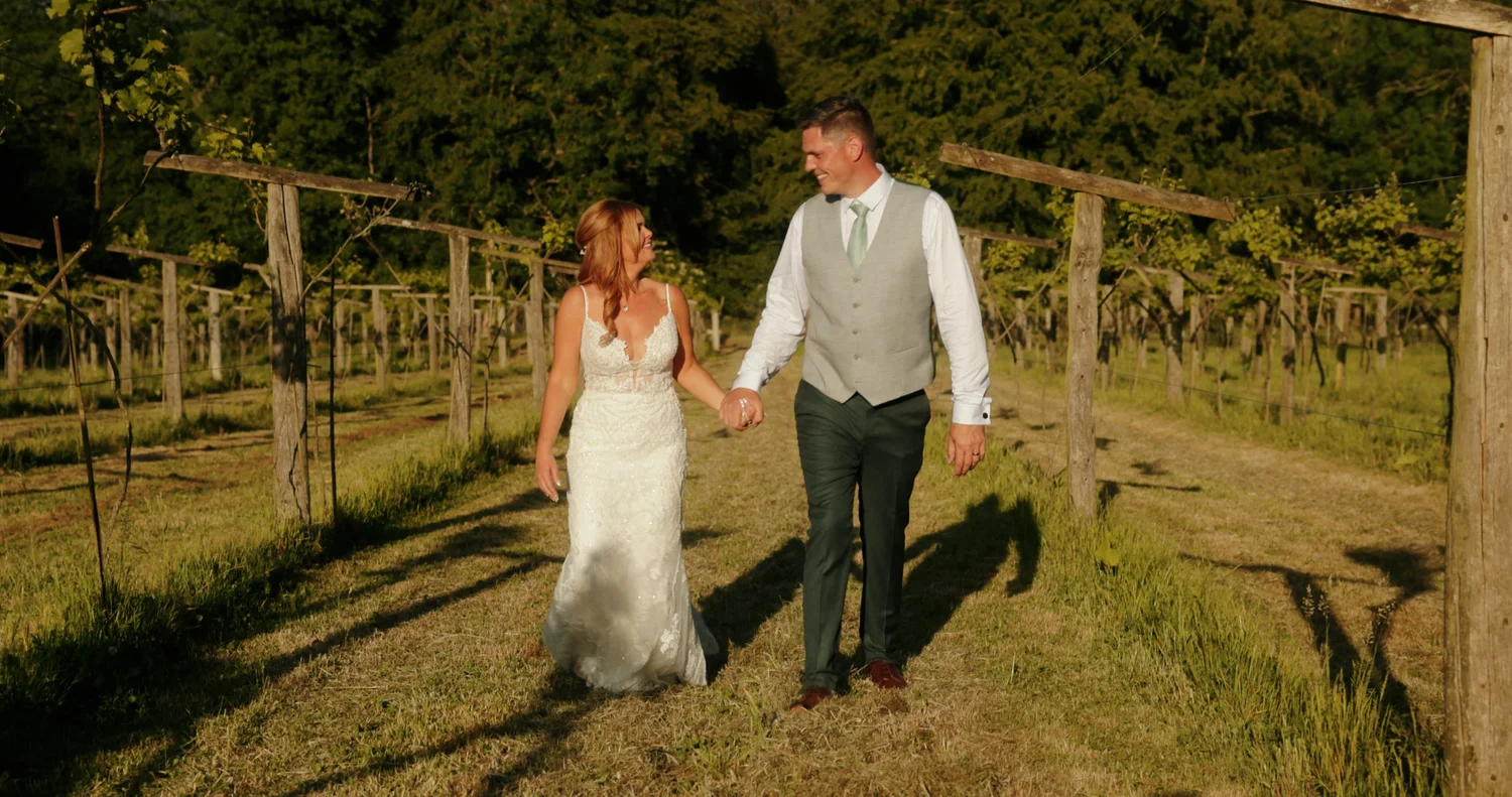 Carli and Neil walking through the vineyard at Old Luxters Barn