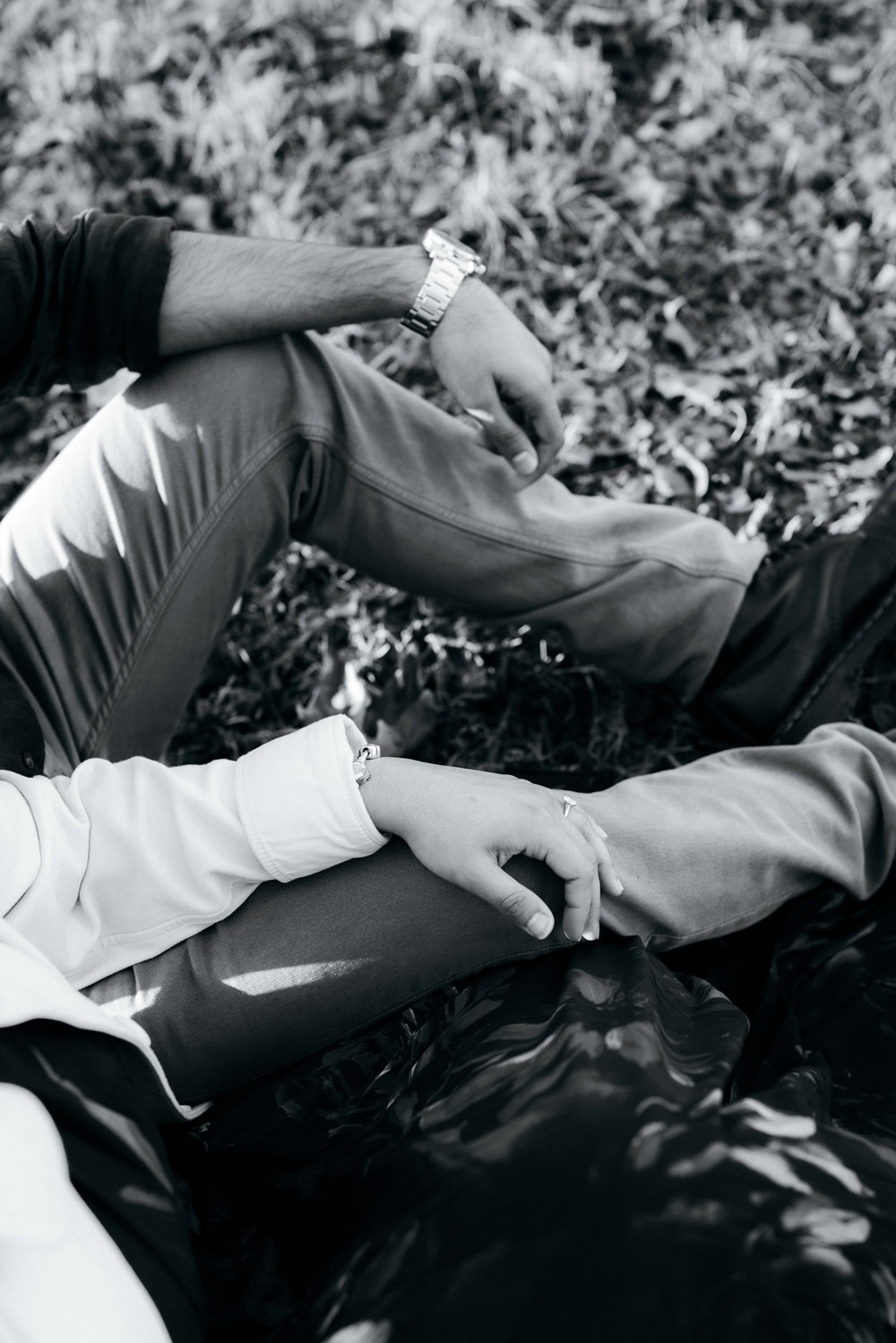 Black and white photograph of the couple holding hands among autumn leaves