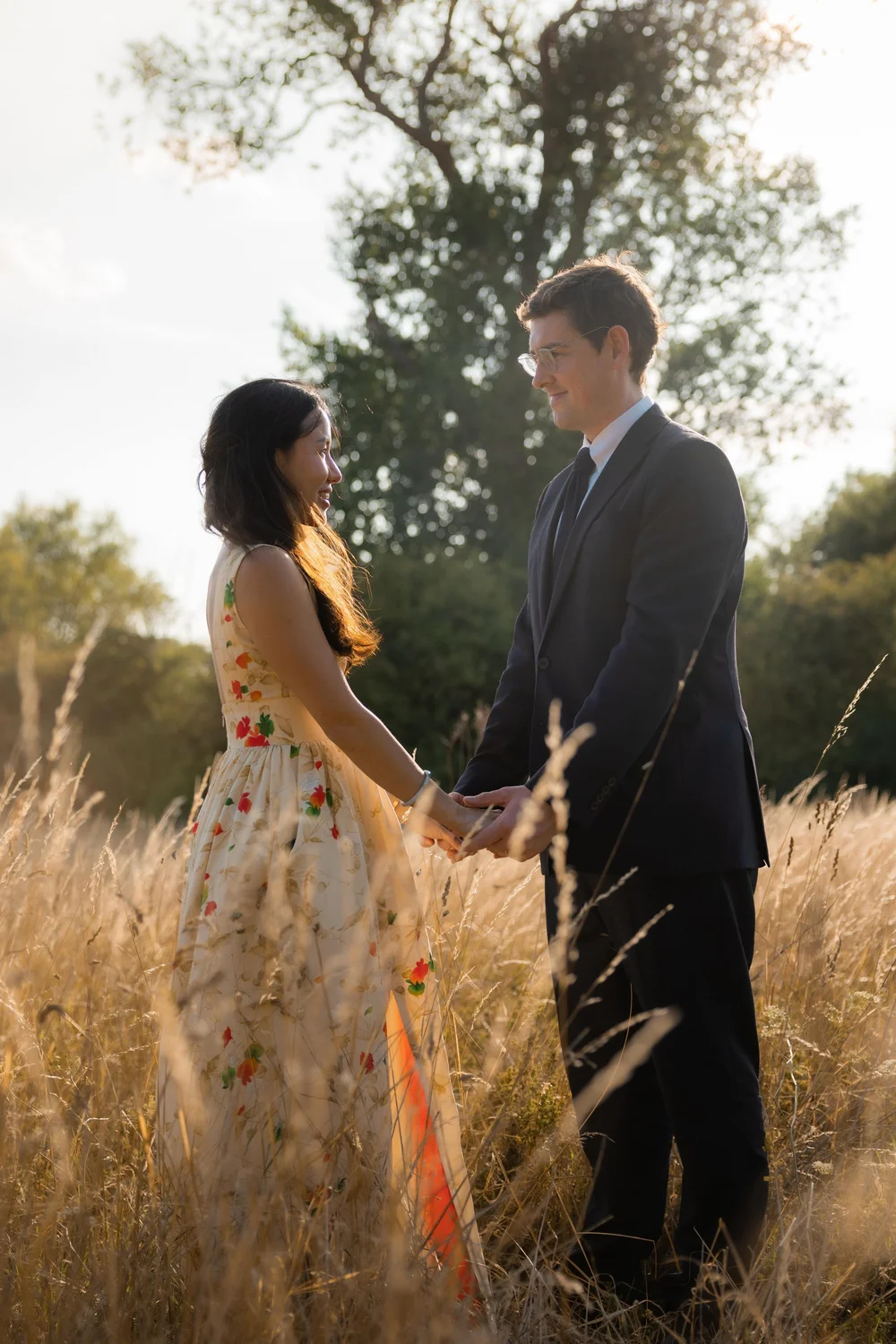 Couple holding hands in long grass in the evening light