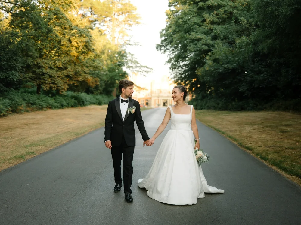 Newlyweds walking together along a tree-lined path