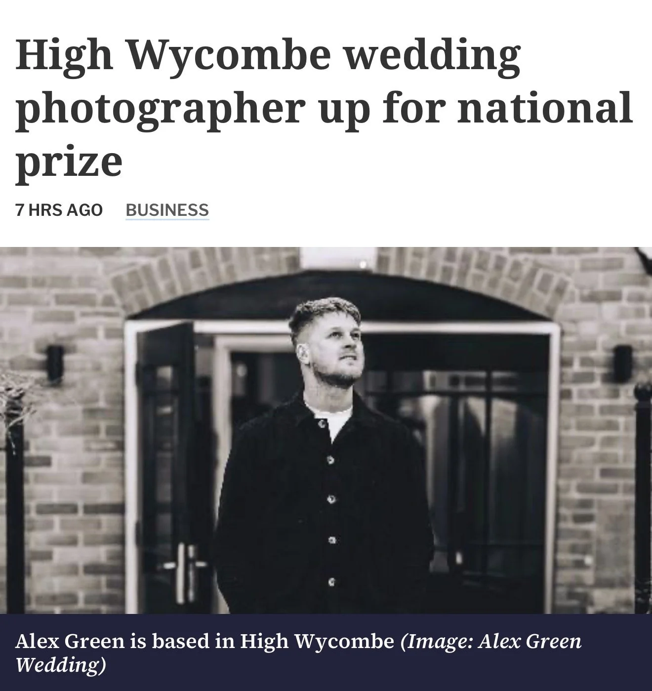 A man with short hair and a beard wearing a black shirt stands in front of a brick building with glass doors, looking upwards. Wedding Photographer Buckinghamshire, High Wycombe