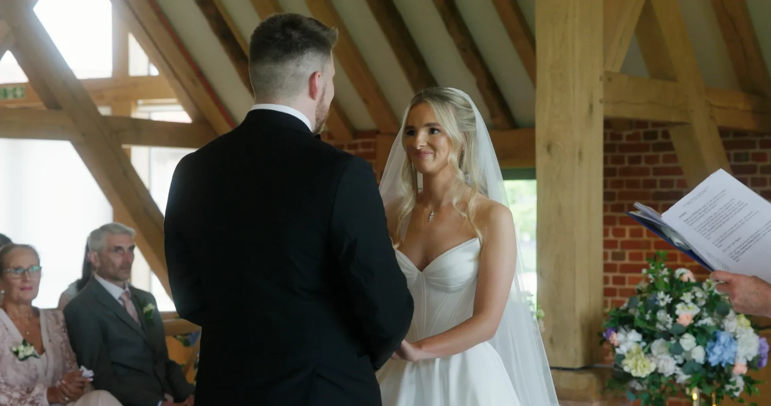 Wedding vows being captured inside the oak-beamed Rackleys ceremony barn