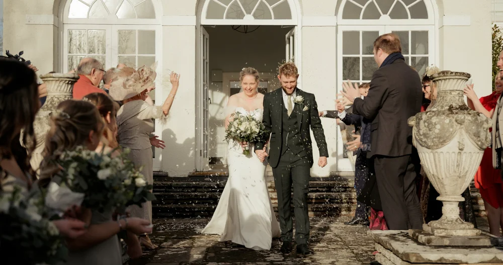 Newlyweds celebrating with confetti on the steps outside their wedding venue