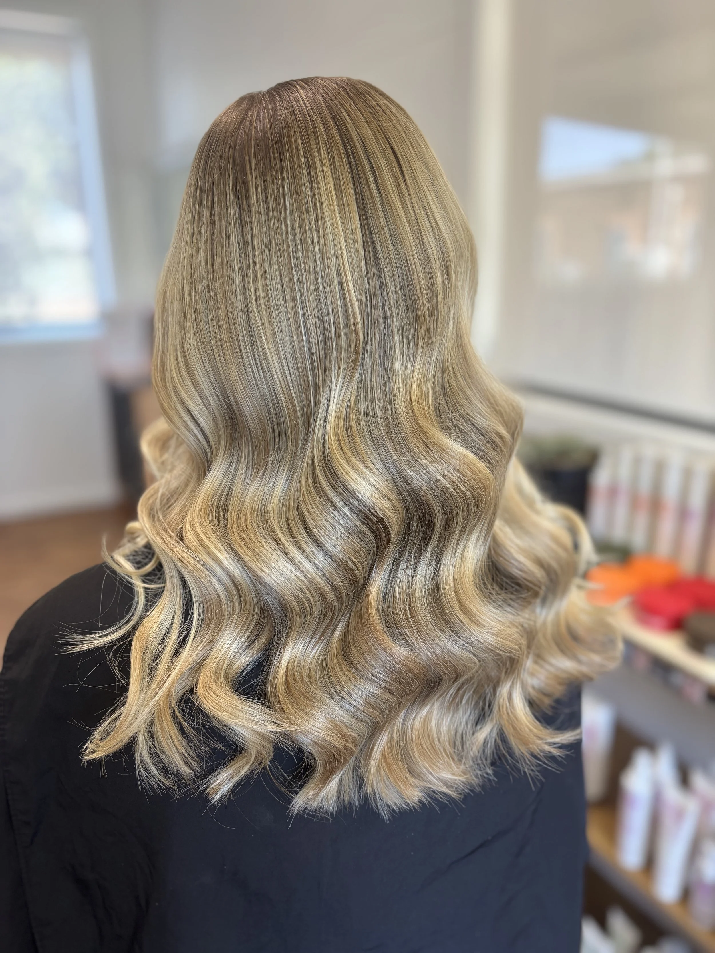 Back view of a woman with long, wavy, blonde hair.