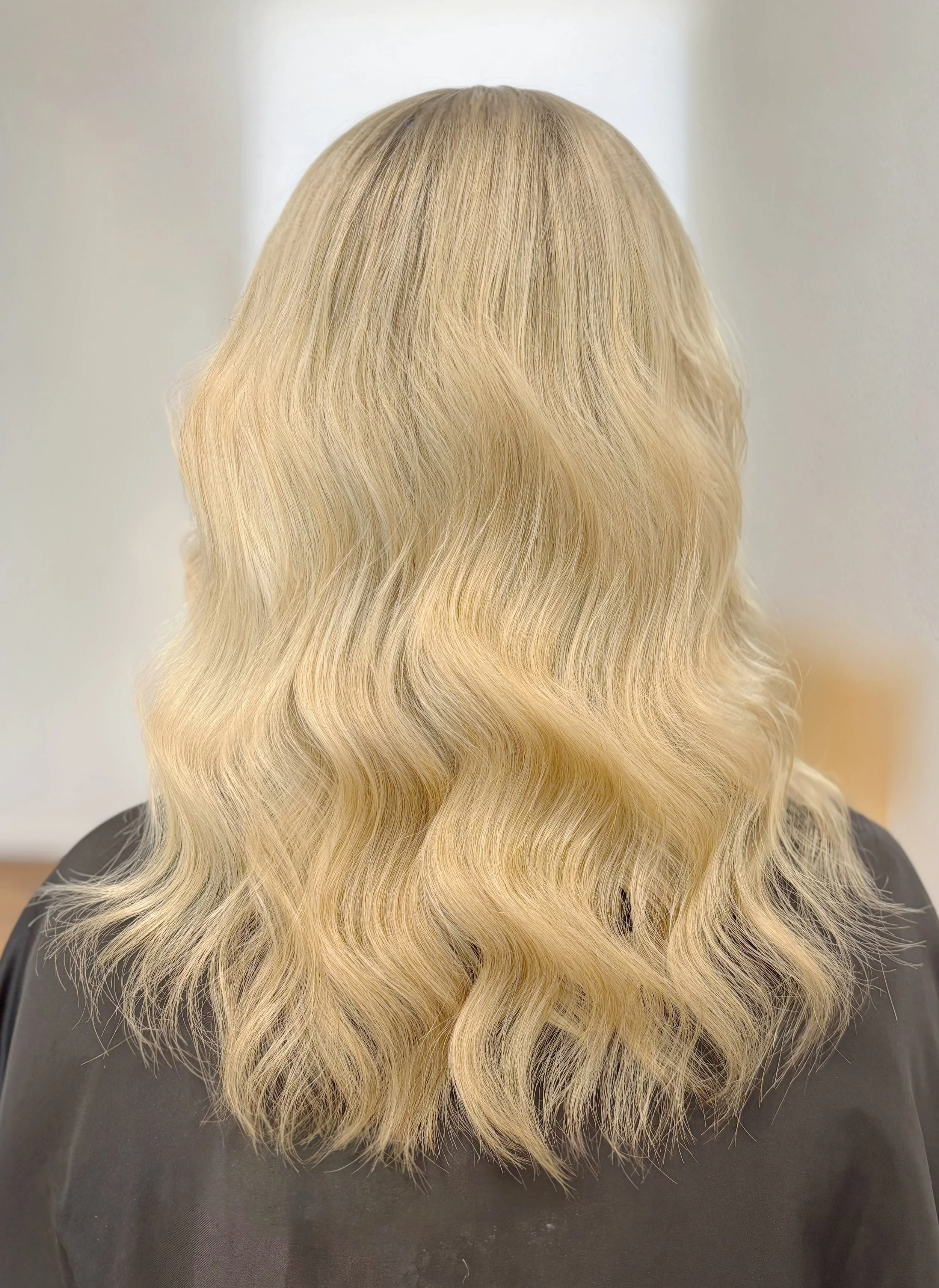 Back of a person with shoulder-length wavy blonde hair.