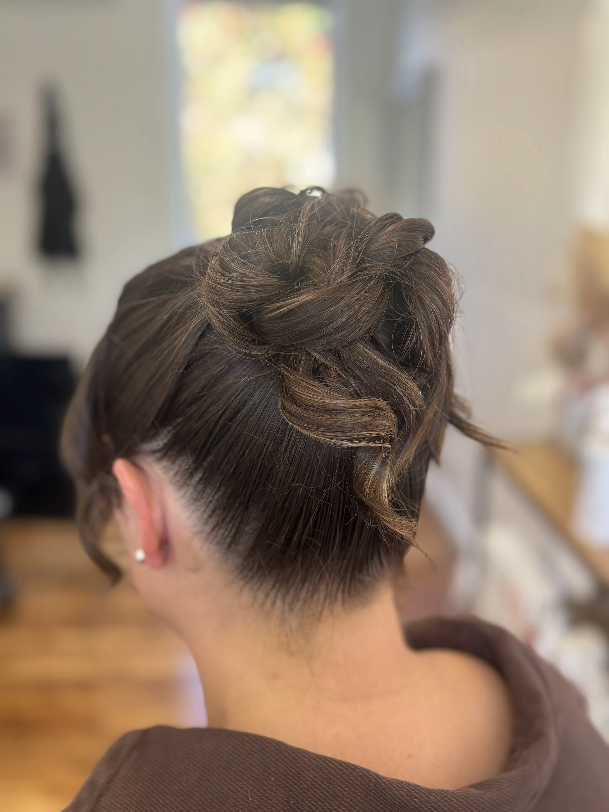 Back view of a person with a short undercut hairstyle and long wavy hair on top, styled in loose curls.